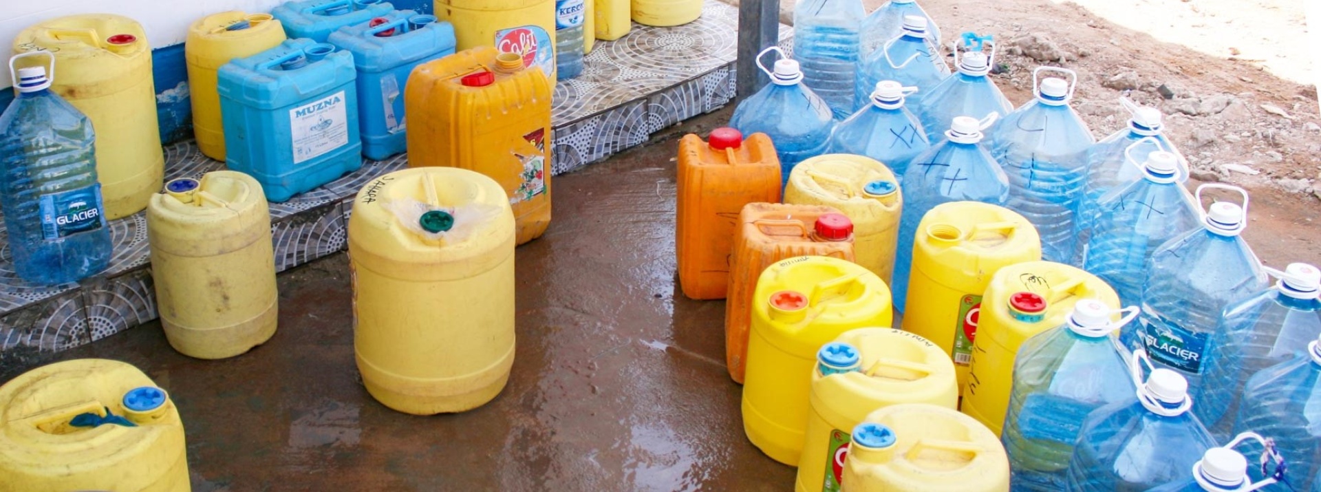 Yellow, orange and blue water canisters in front of a WaterKiosk in Kenya