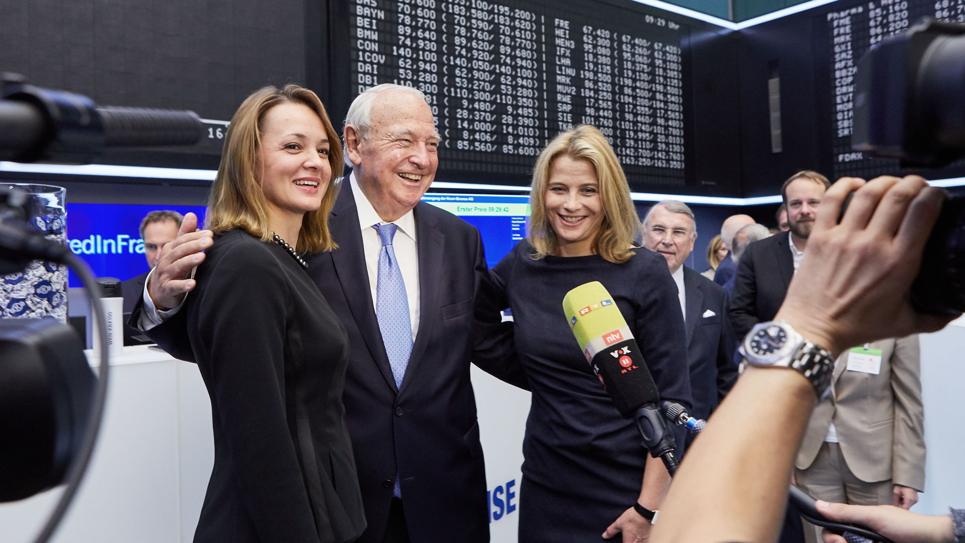 Heinz Hermann Thiele stands in front of TV cameras on the trading floor of the Frankfurt Stock Exchange; all three laugh and beam after the successful IPO of the Knorr-Bremse share.