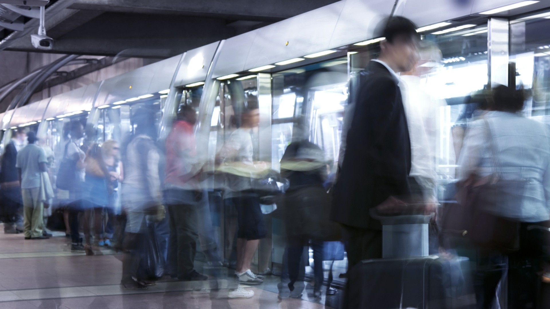 Many people get on and off the subway platform.