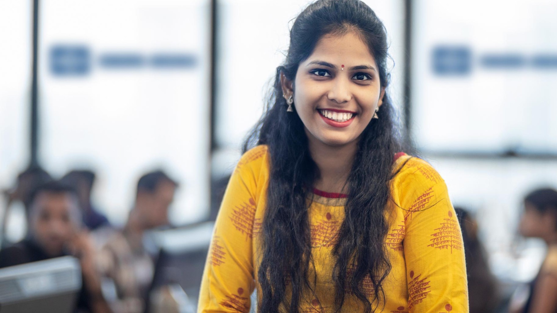 A female employee in close-up in the office of the Knorr-Bremse Technology Center India. She is wearing traditional Indian clothing.