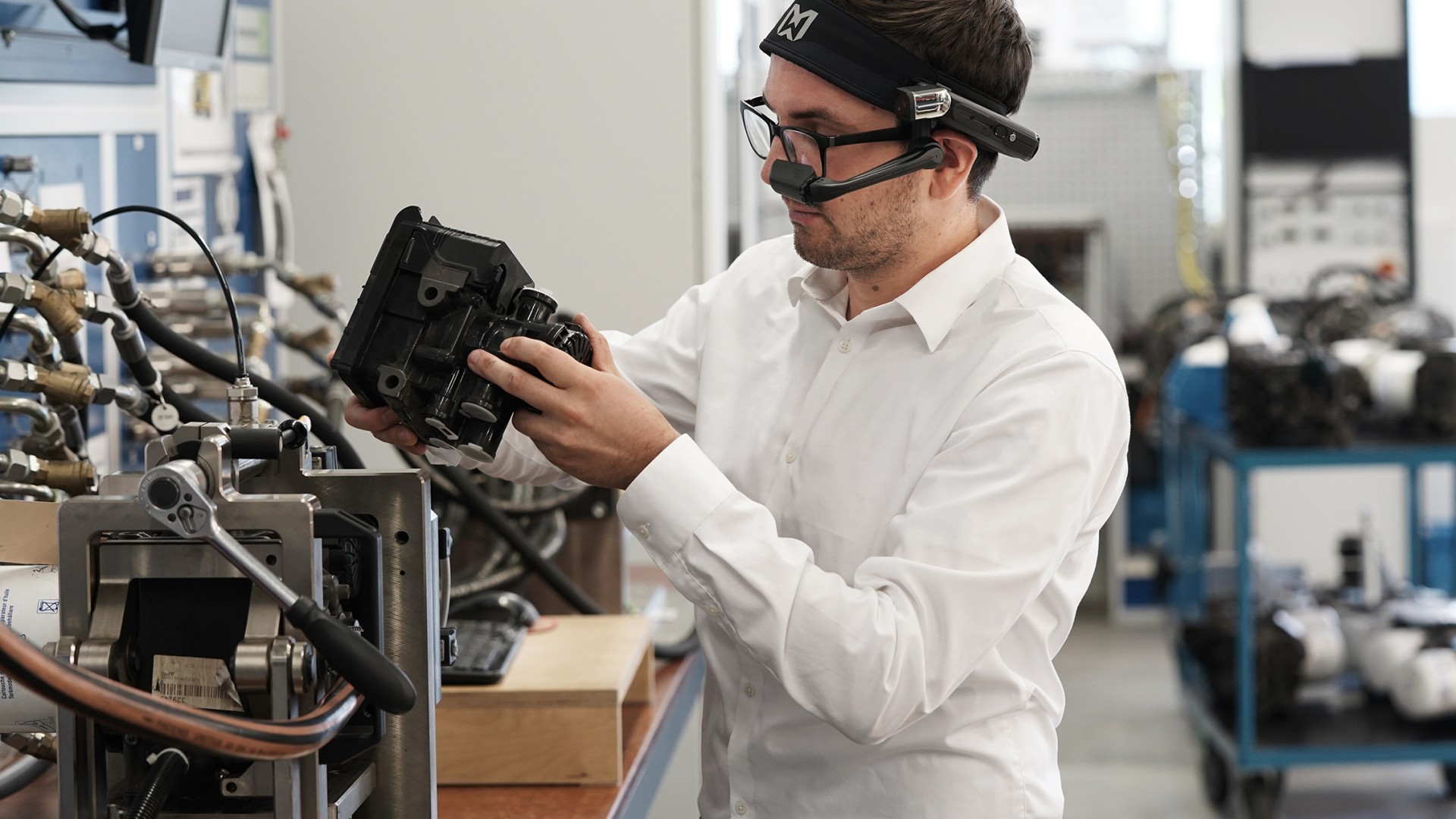 A Knorr-Bremse employee looks at a technical product through AR glasses.