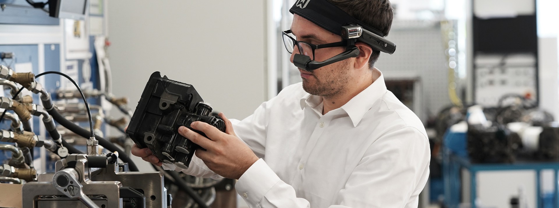 A Knorr-Bremse employee looks at a technical product through AR glasses.