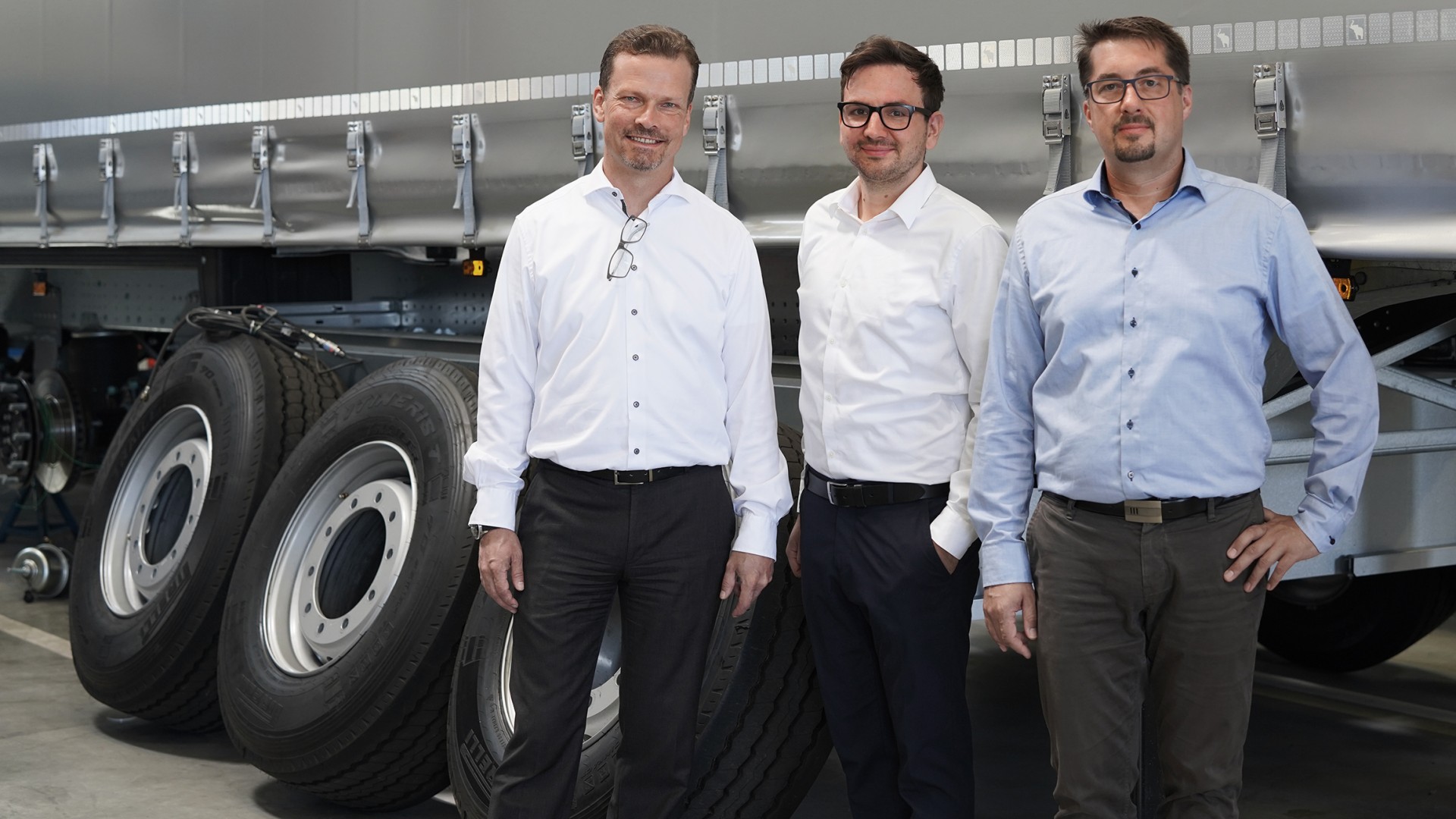 The three-strong team of experts for AR glasses from Knorr-Bremse Commercial Vehicle Systems stands in front of a truck in the workshop.