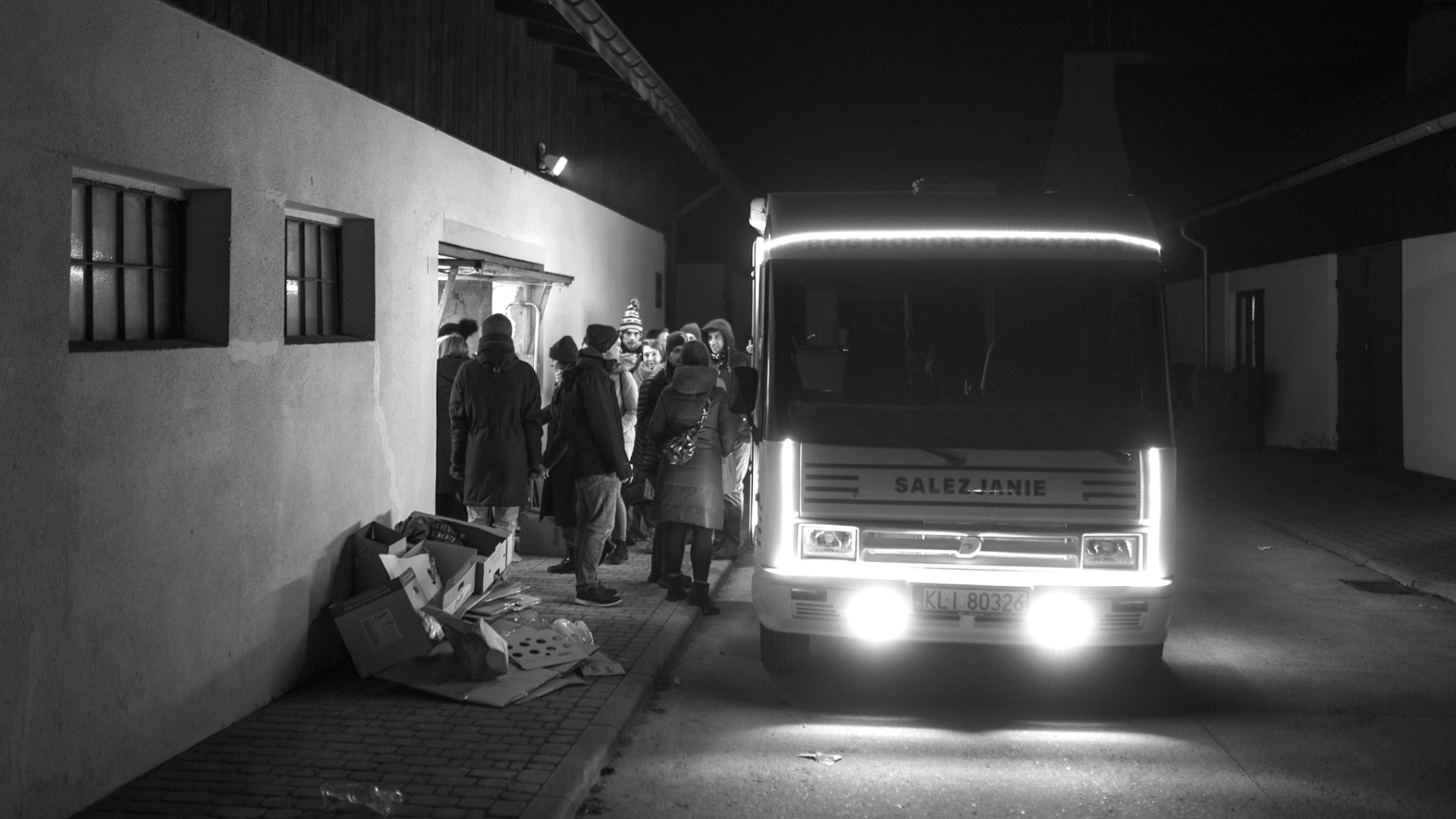 Ein Bus holt im Dunkeln eine Gruppe Ukrainierinnen und Ukrainer vor einem Haus ab, um sie aus zu evakuieren.
