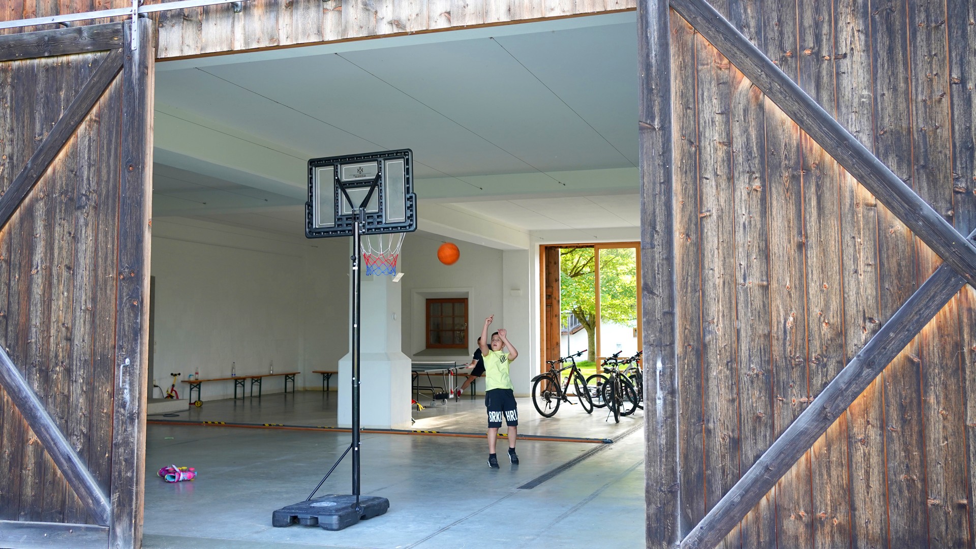 Ein Junge wirft auf einen Basketballkorb in einer ausgebauten Scheune auf dem Hofgut Eck.