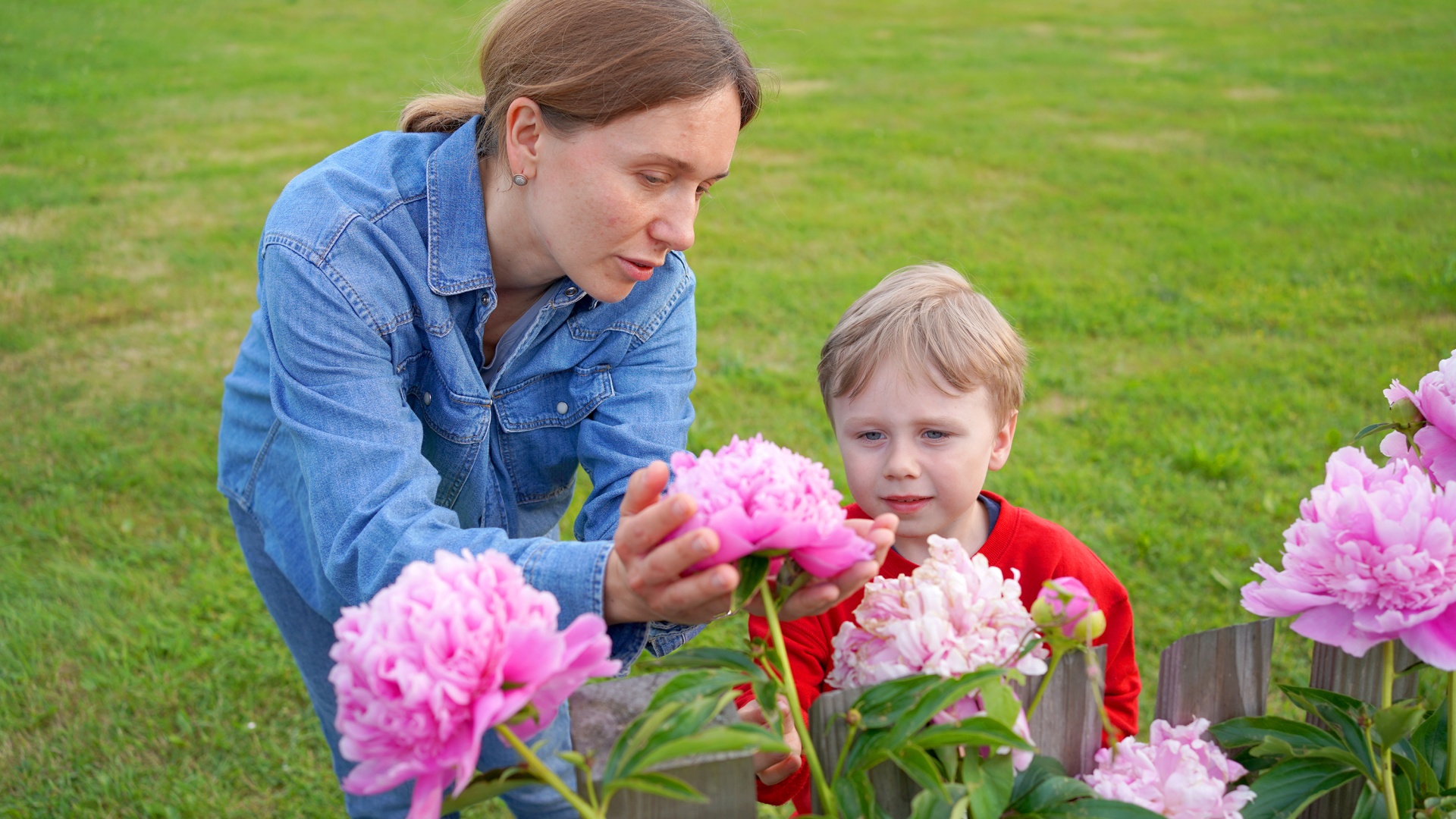 Eine ukrainische Mutter zeigt ihrem kleinen Jungen die blühenden Pfingstrosen im Garten des Hofgut Eck.