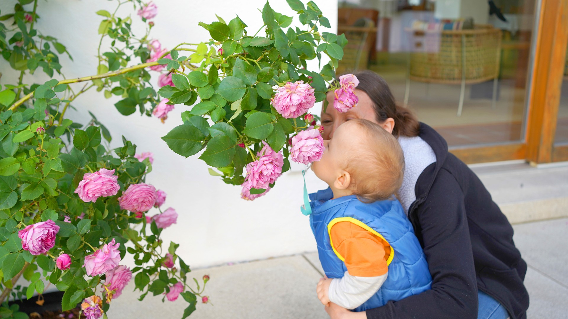 Ein kleiner ukrainischer Junge riecht mit seiner Mama an Rosenblüten.