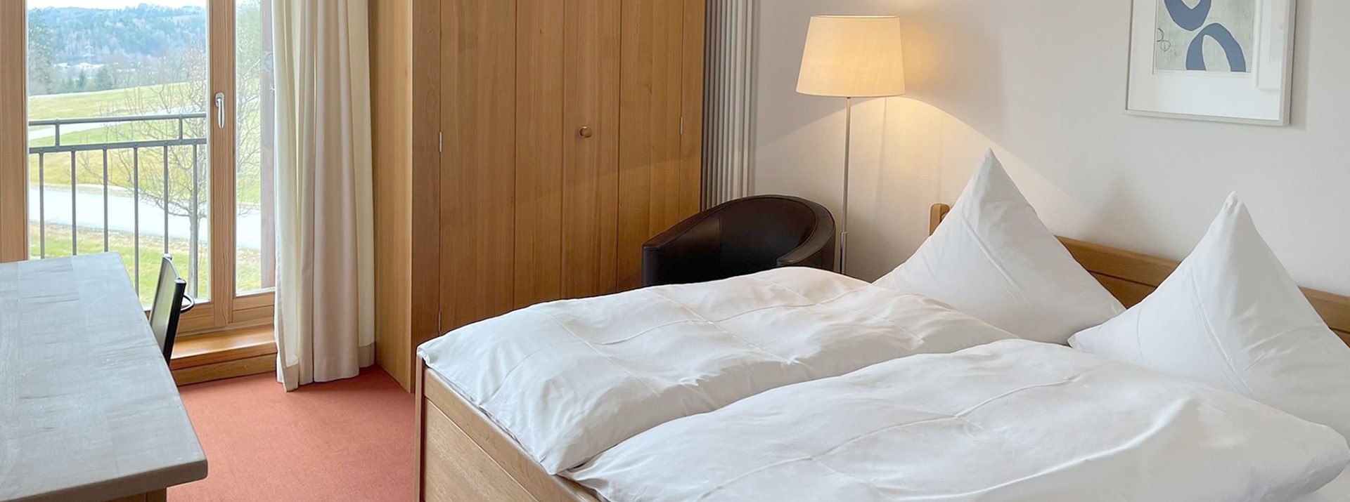 A room with a double bed and a view of the greenery at Hofgut Eck.