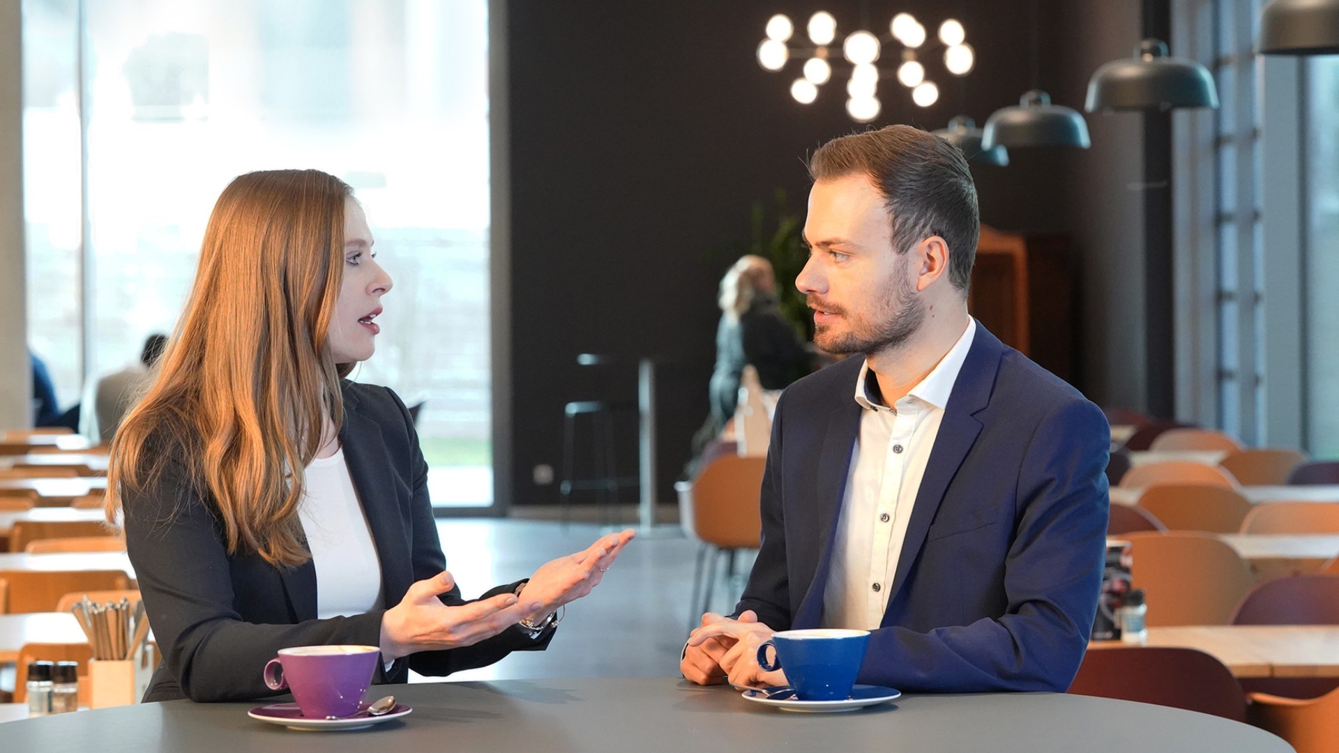 The two trainees Elina Steinke and Johannes Weth chat at a table in the cafeteria at the Knorr-Bremse site in Munich.