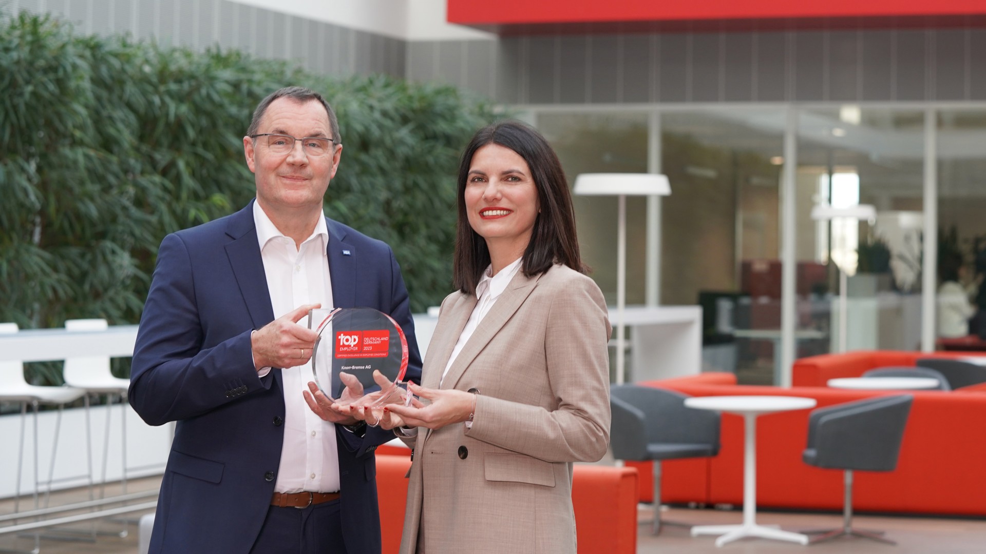 Klaus Remmler, Konzernpersonalleiter der Knorr-Bremse AG, und Berna Tulga-Akcan, HR-Spezialistin Hochschulmarketing, halten gemeinsam den Top Employer Award in ihren Händen.