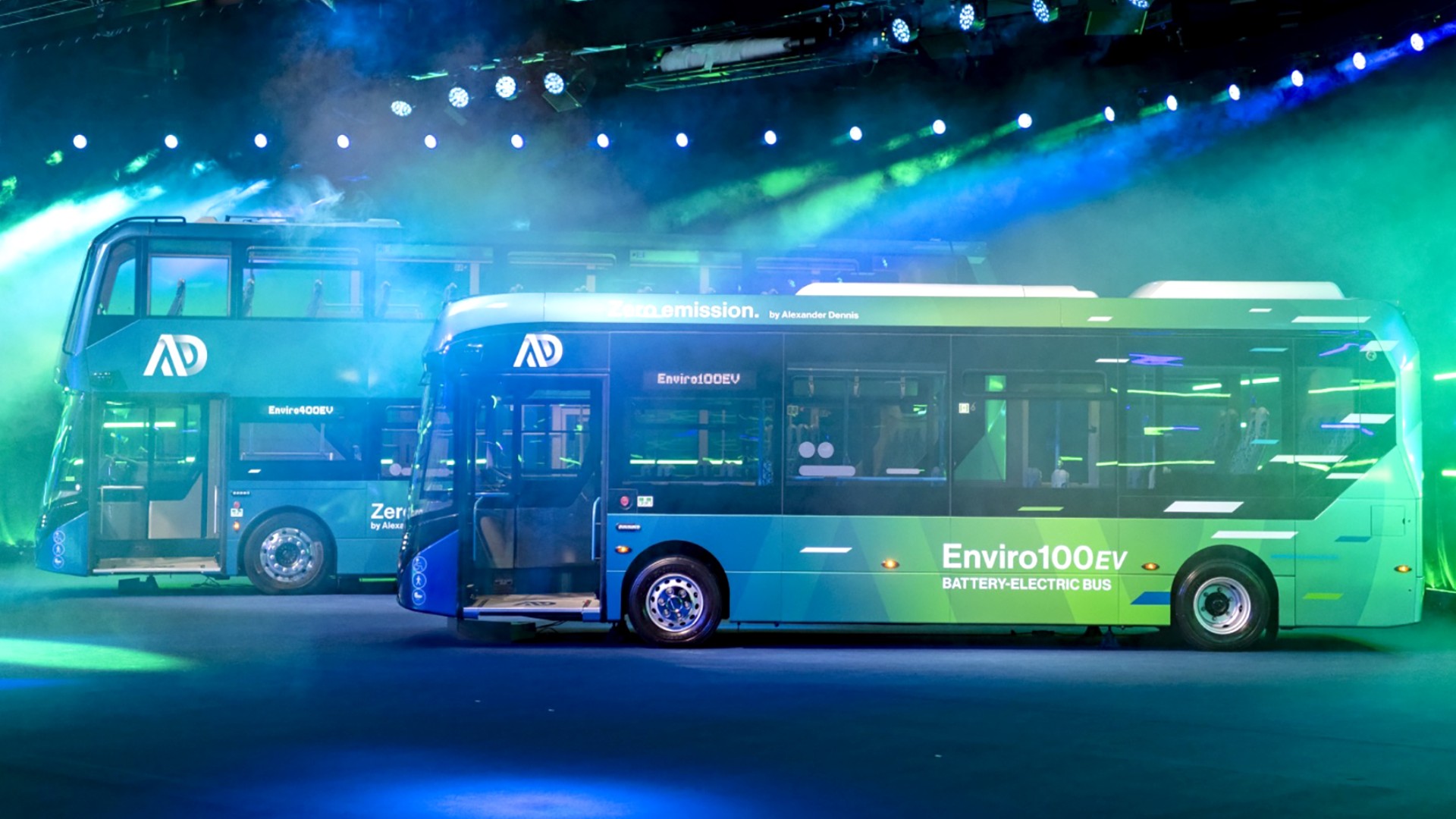 Bereit für den Launch: Die beiden neuen Busmodelle Enviro 400EV und Enviro 100 EV stehen bunt beleuchtet im Showroom.