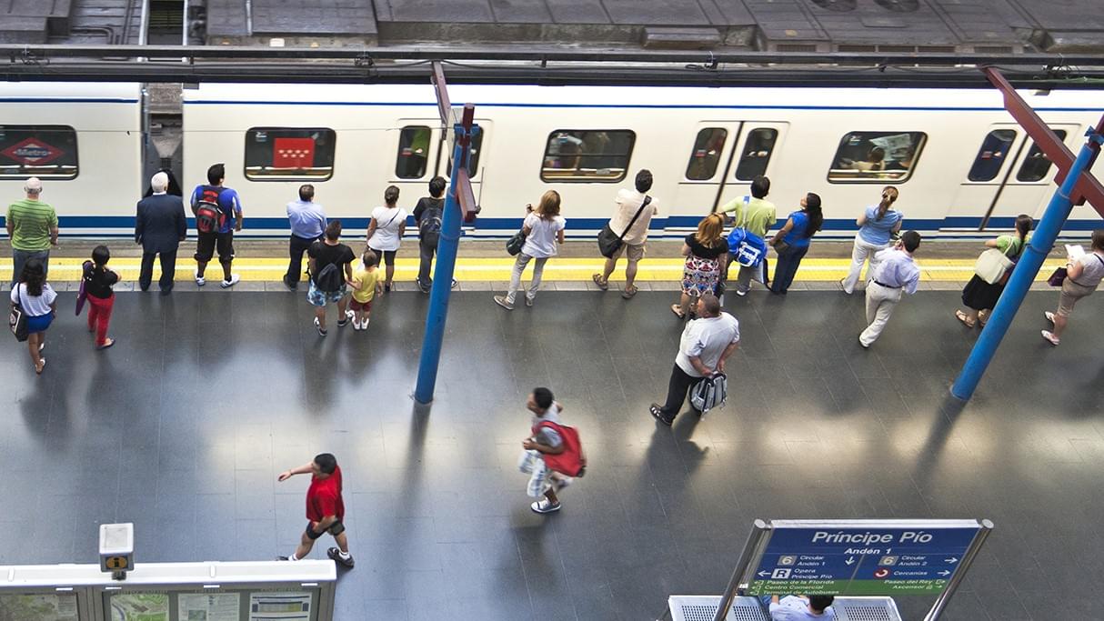 Passengers stand on the platform in front of a Madrid metro waiting for the doors to open to board.