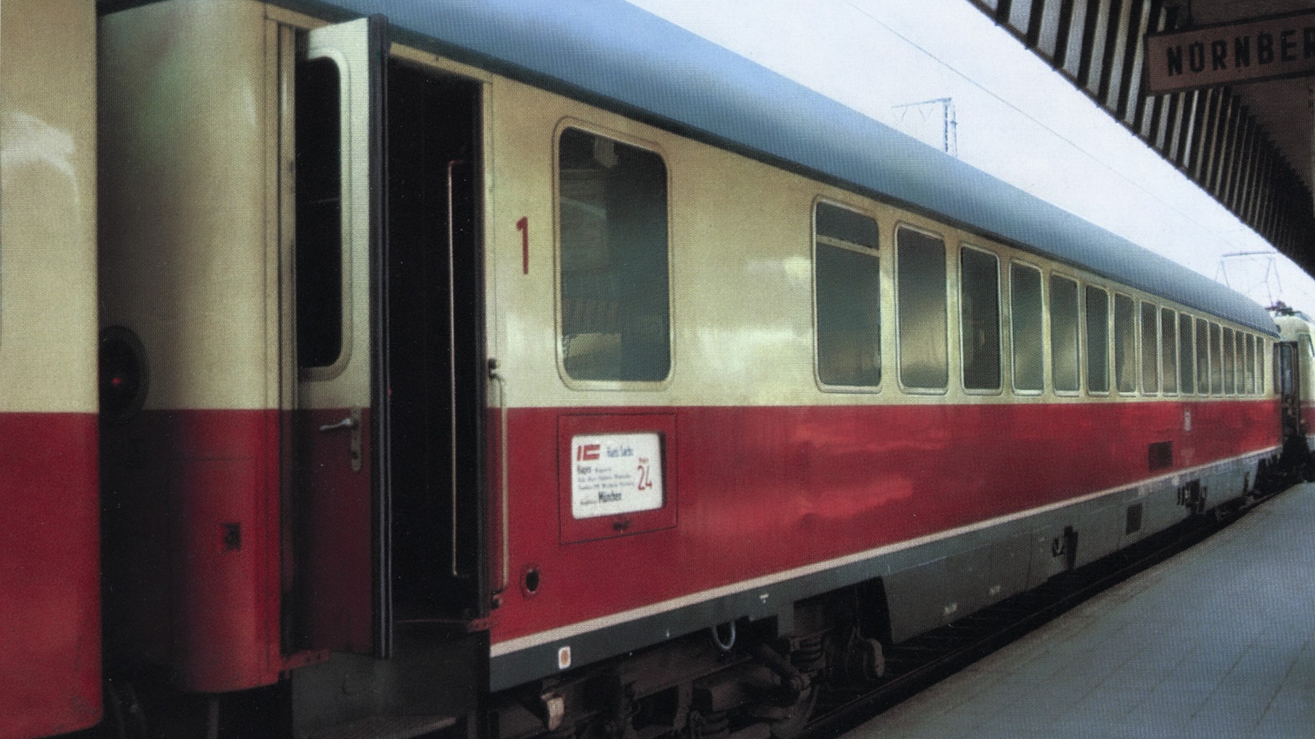 First‑class passenger coach with an open door at a station platform