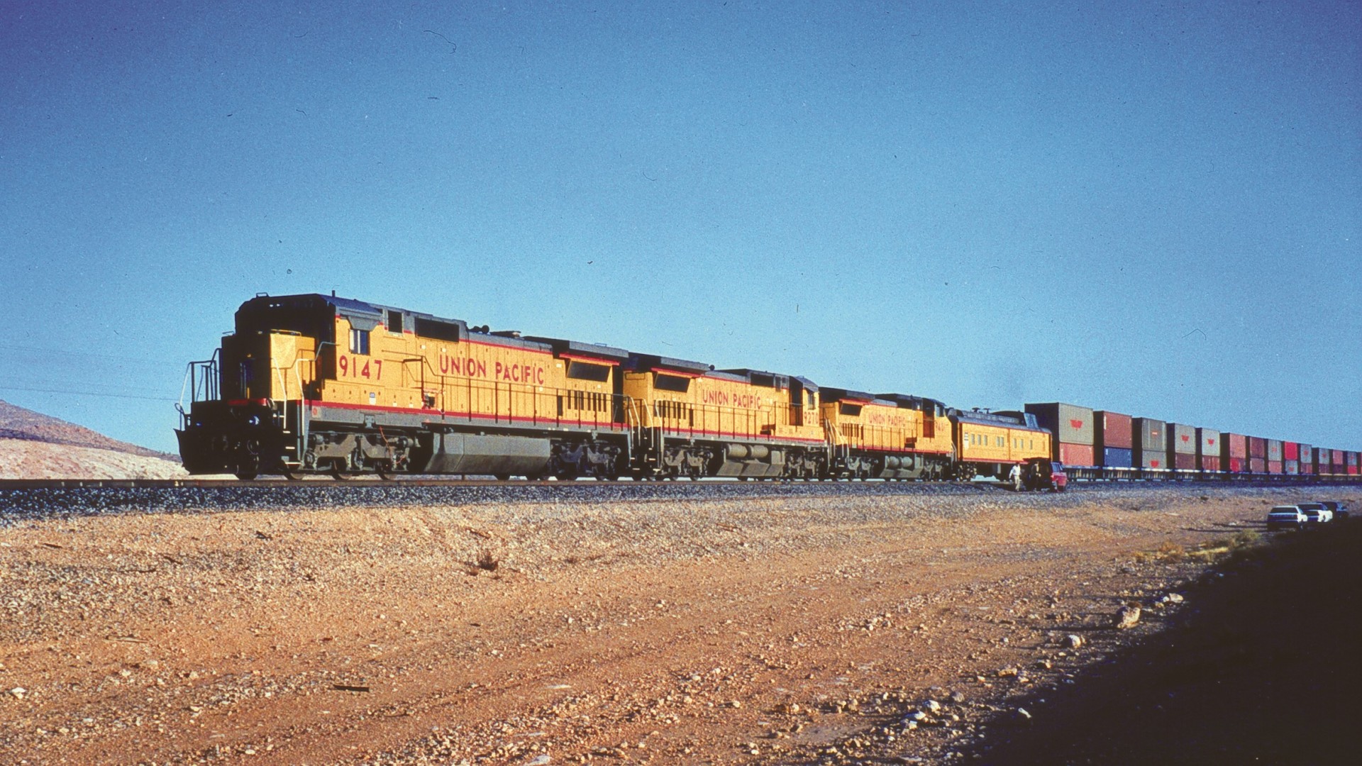 Güterzug der Union Pacific mit mehreren gelben Diesellokomotiven und Containerwagen in Wüstenlandschaft