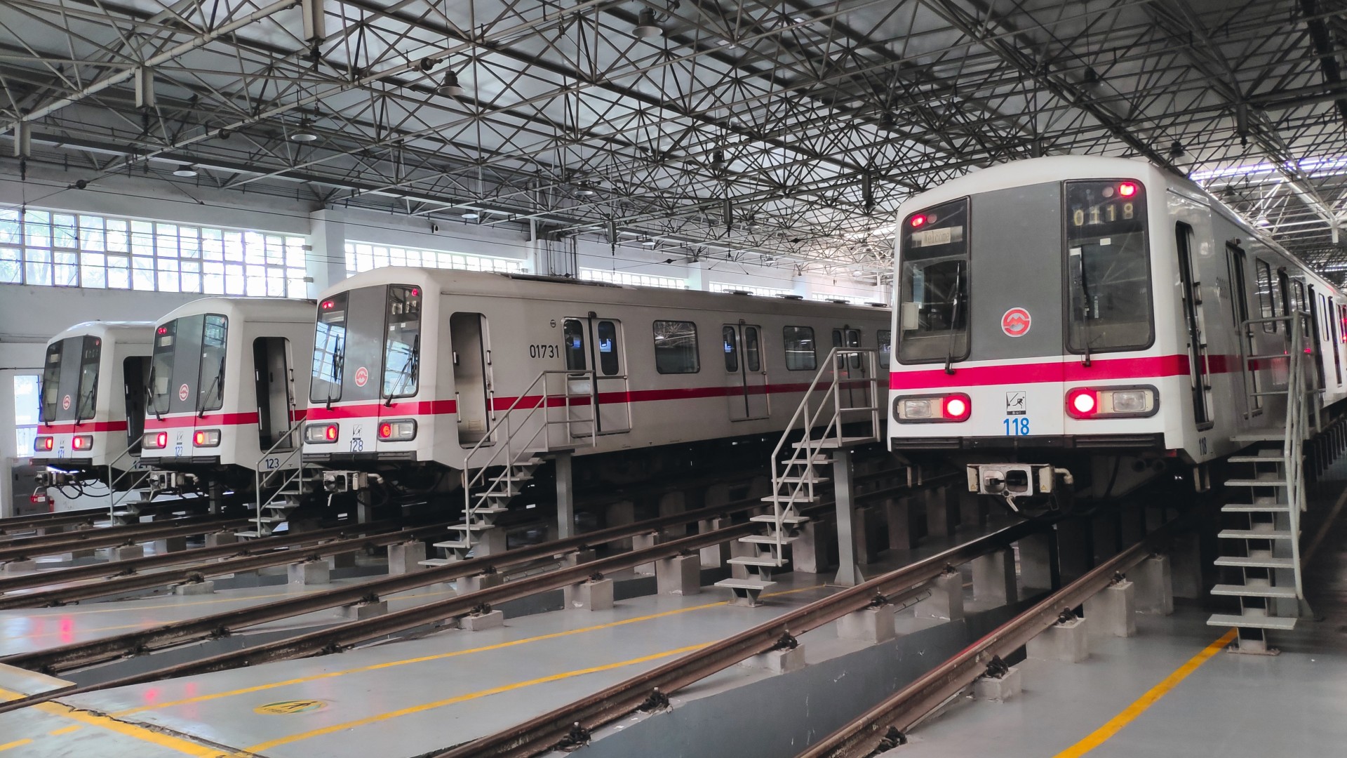 Multiple metro trains in a maintenance hall on elevated tracks