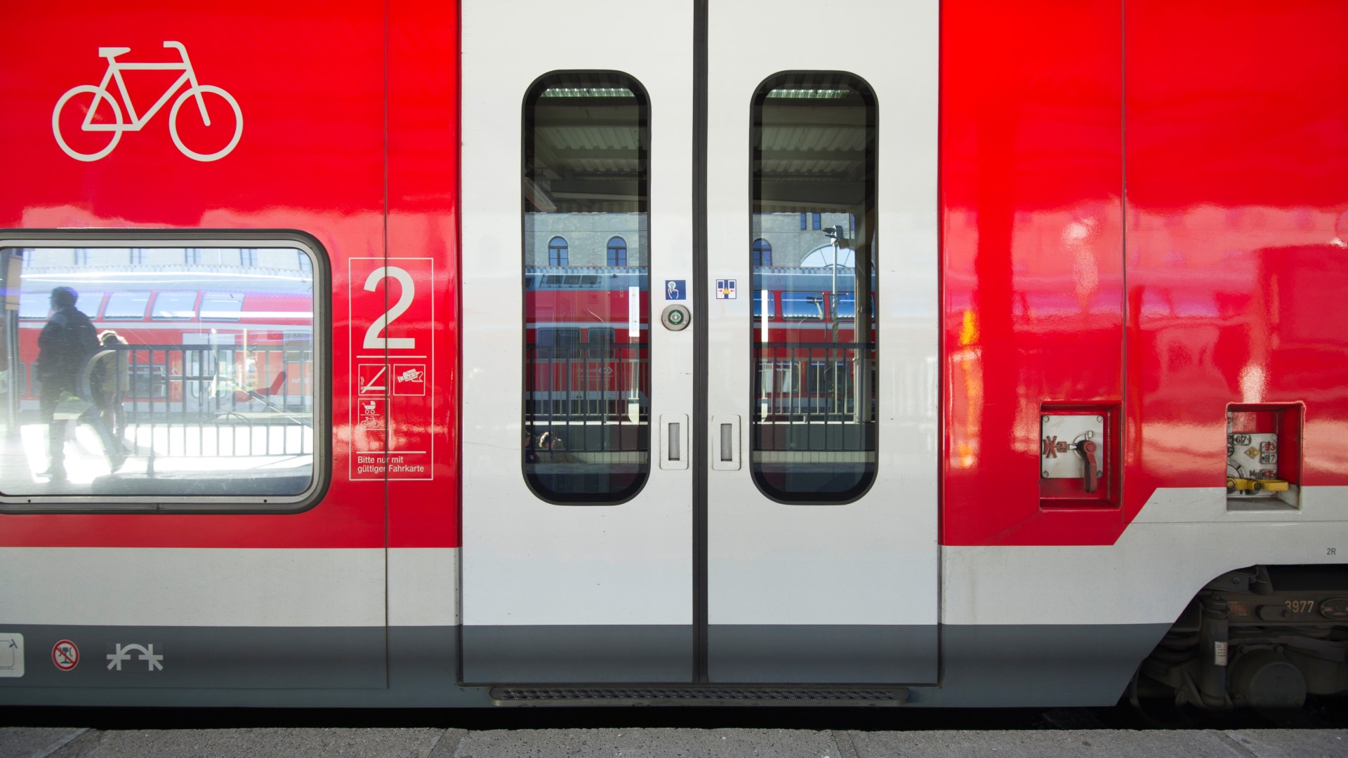 Geschlossene Zugtür eines roten Regionalzuges am Bahnsteig