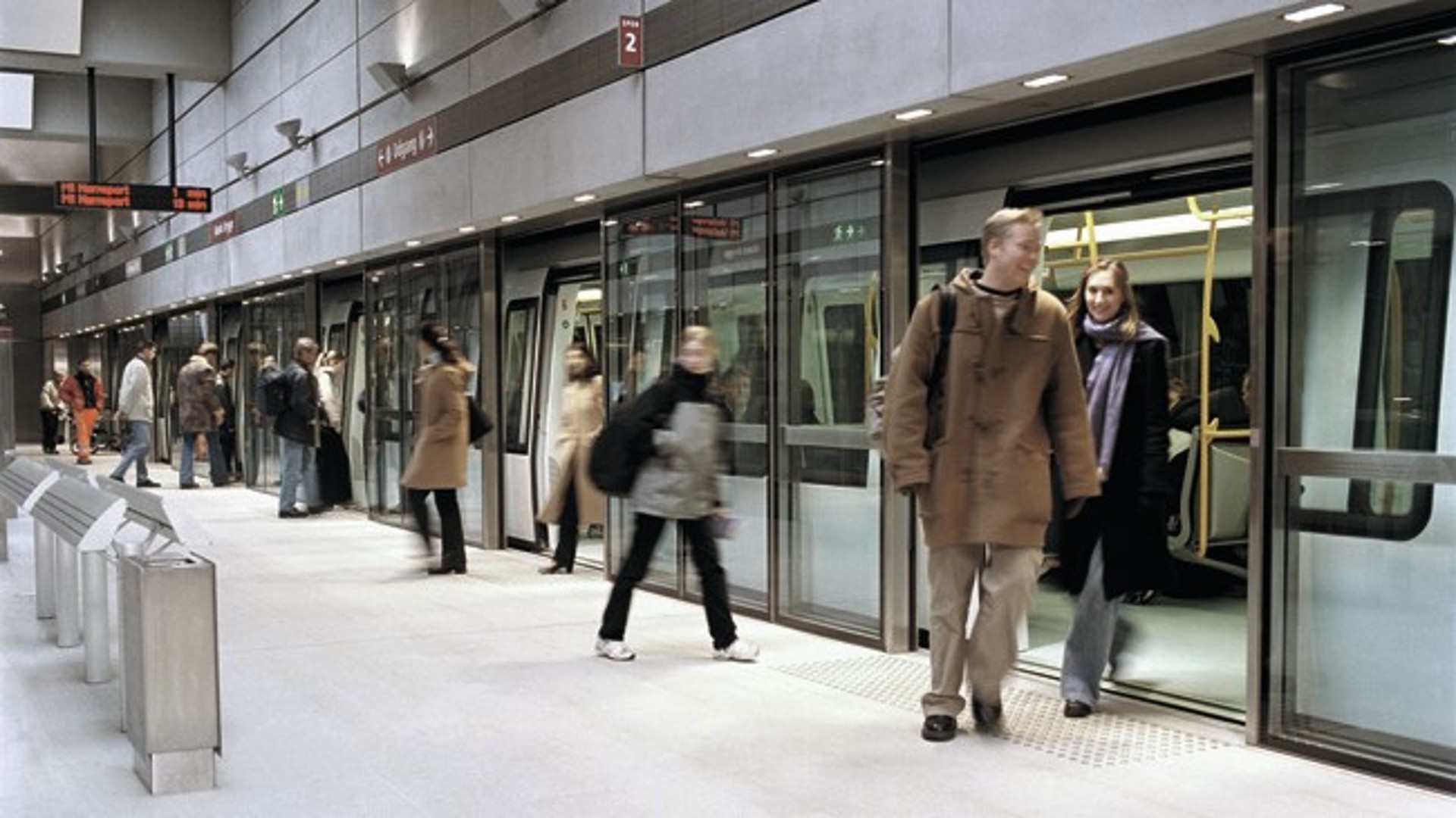 Metro station with platform screen doors as passengers board and exit the train
