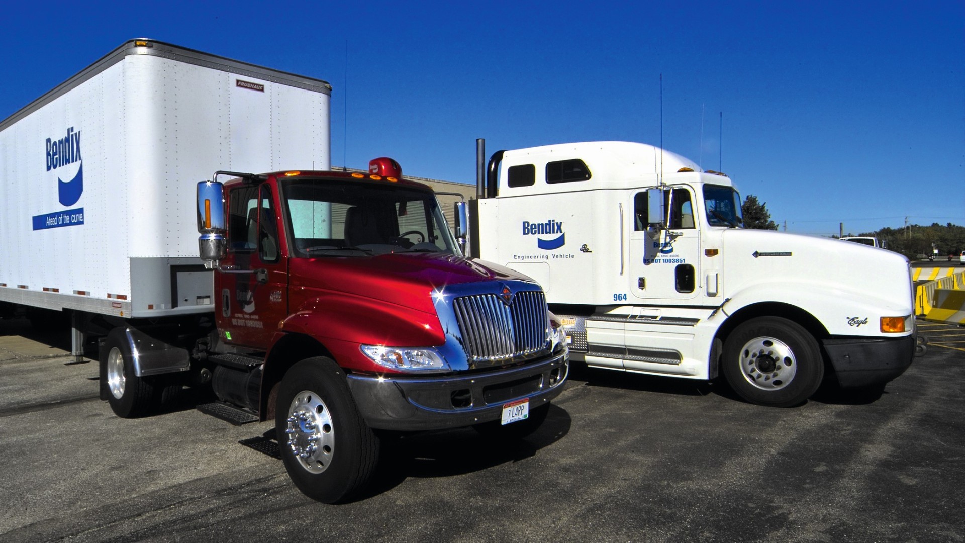 Two American trucks with Bendix branding on an industrial lot
