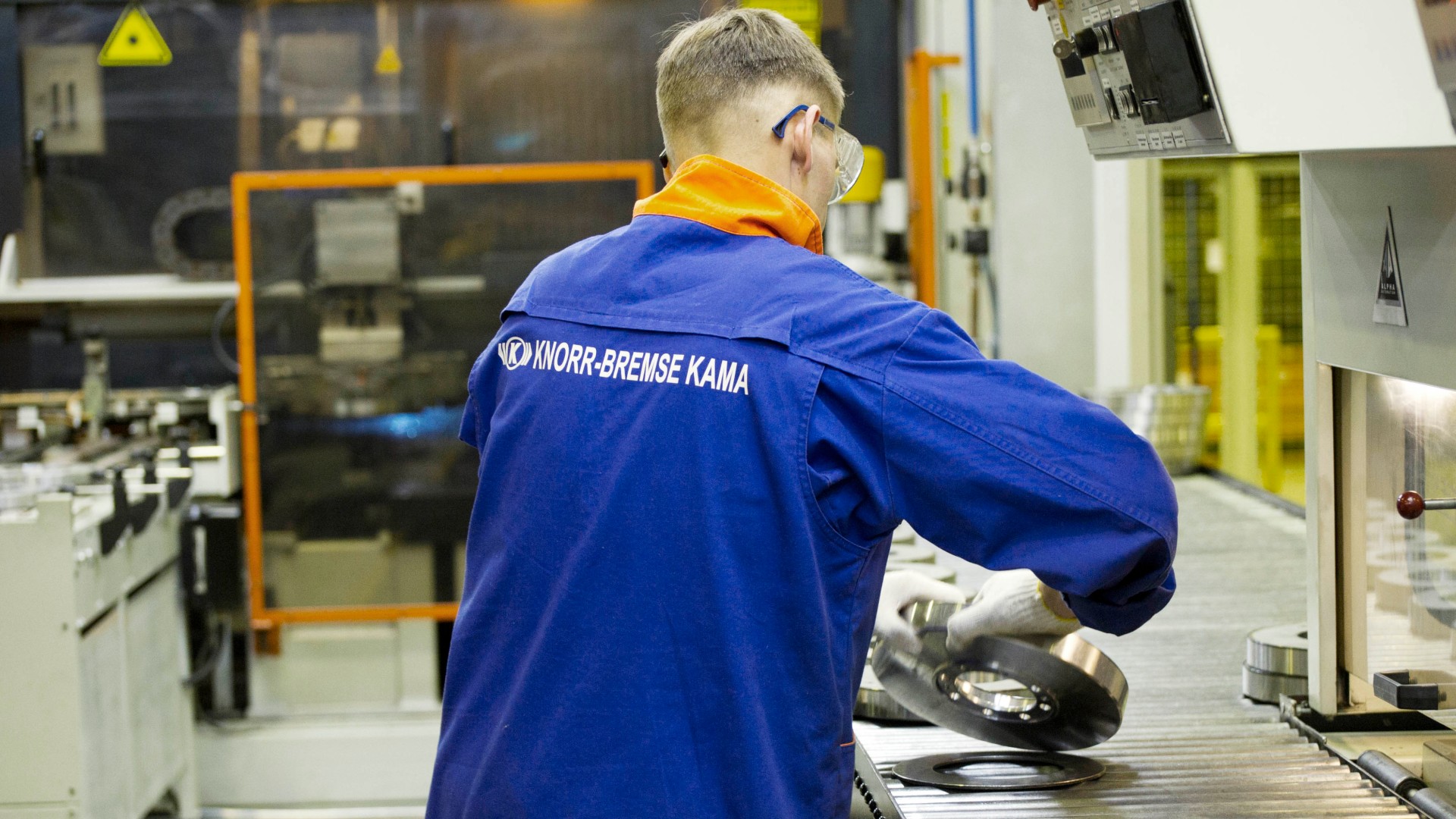 Mitarbeiter in Knorr‑Bremse KAMA Arbeitskleidung an einer Produktionslinie