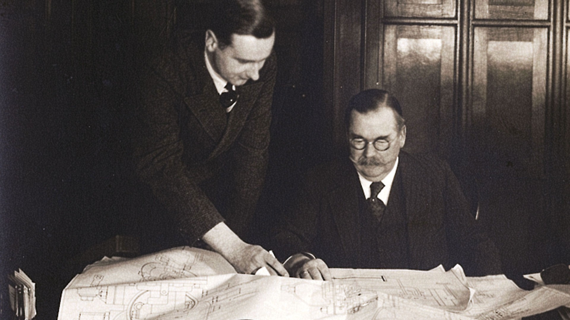 Zwei Personen bei der gemeinsamen Arbeit an technischen Zeichnungen in einem Büro, historische Aufnahme um 1935