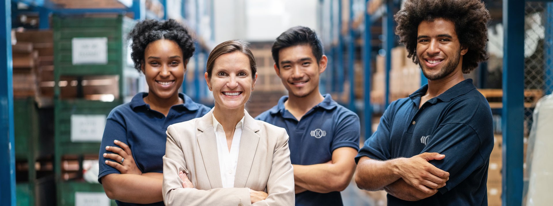 Diverse team of employees in an industrial setting with a female leader standing confidently in front, symbolizing modern leadership at Knorr‑Bremse