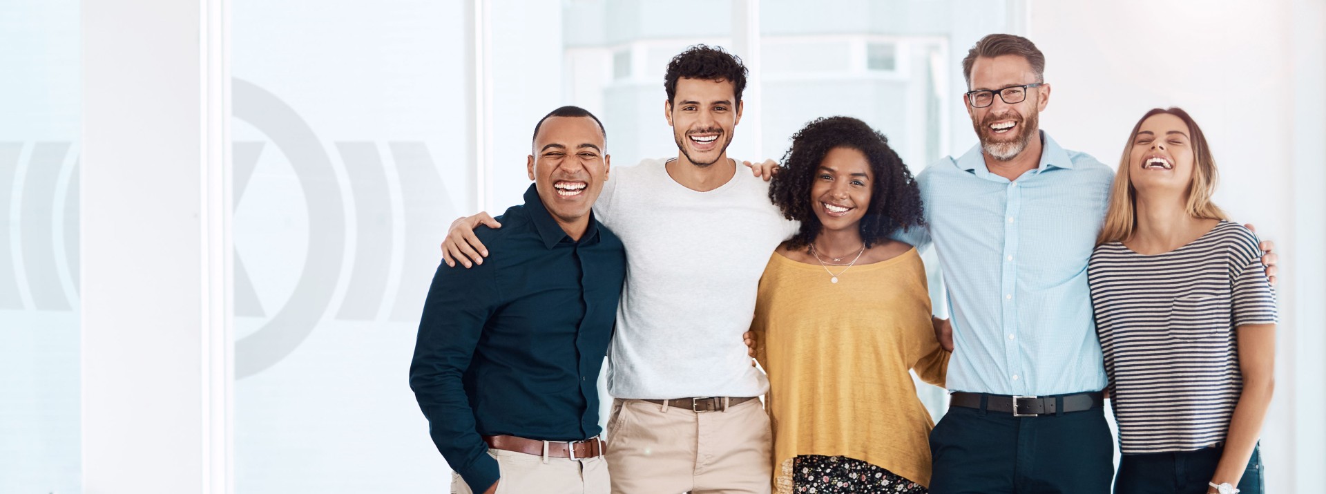 Diverse Gruppe von Mitarbeitenden unterschiedlichen Alters und Geschlechts aus verschiedenen kulturellen Hintergründen, die Arm in Arm stehen und Teamgeist sowie die Unternehmenskultur von Knorr‑Bremse symbolisieren