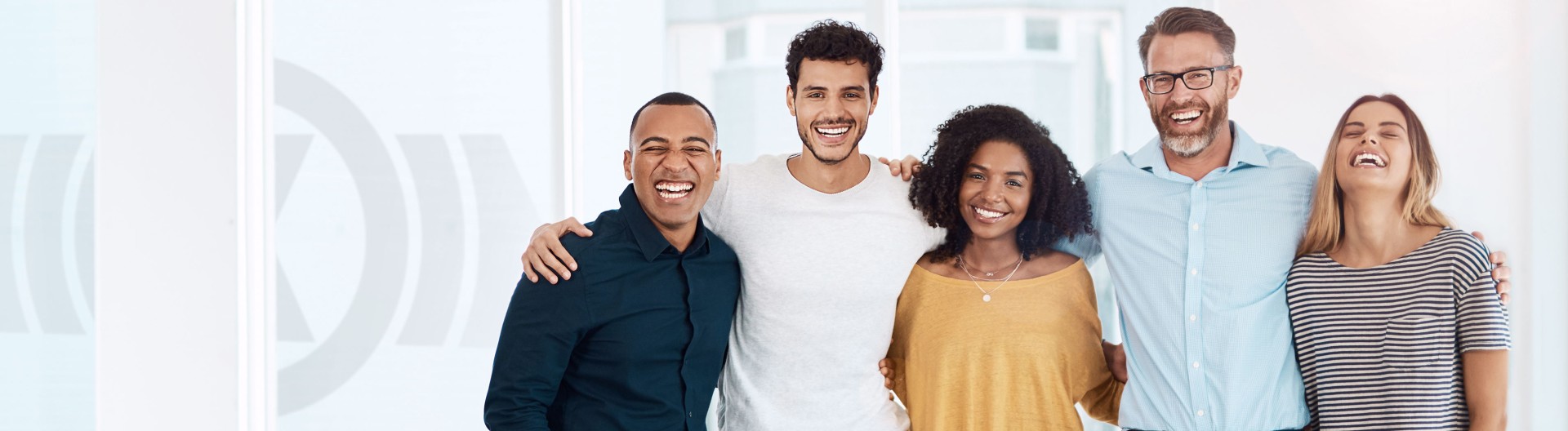 Diverse group of employees of different ages, genders and cultural backgrounds standing arm in arm, symbolizing team spirit and Knorr‑Bremse’s corporate culture
