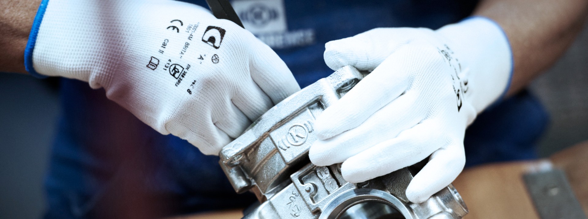 Handarbeit an einem Knorr‑Bremse Stahlbauteil mit weißen Industriehandschuhen als Symbol für Präzision, Qualitätsanspruch und Exzellenz