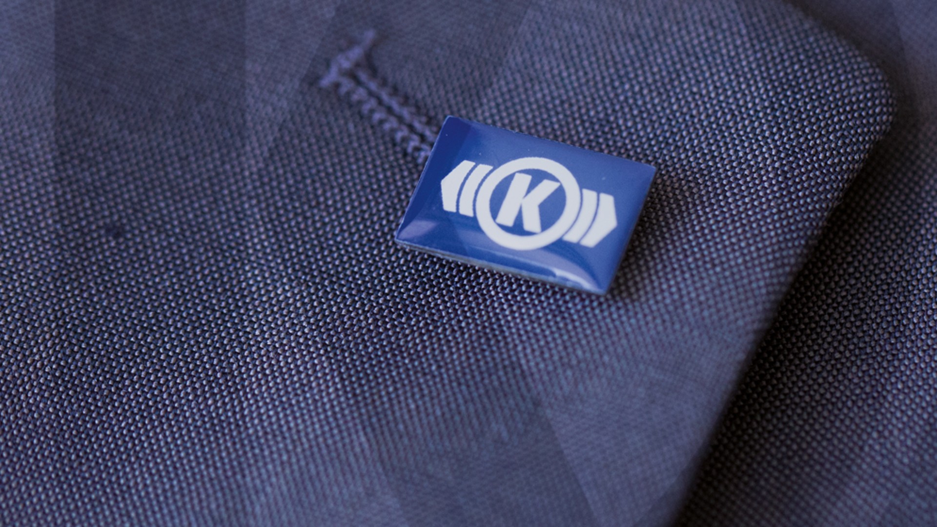 Knorr‑Bremse Ansteckpin mit Unternehmenslogo am Revers eines Anzugs – Symbol für Unternehmenswerte und Unternehmenskultur