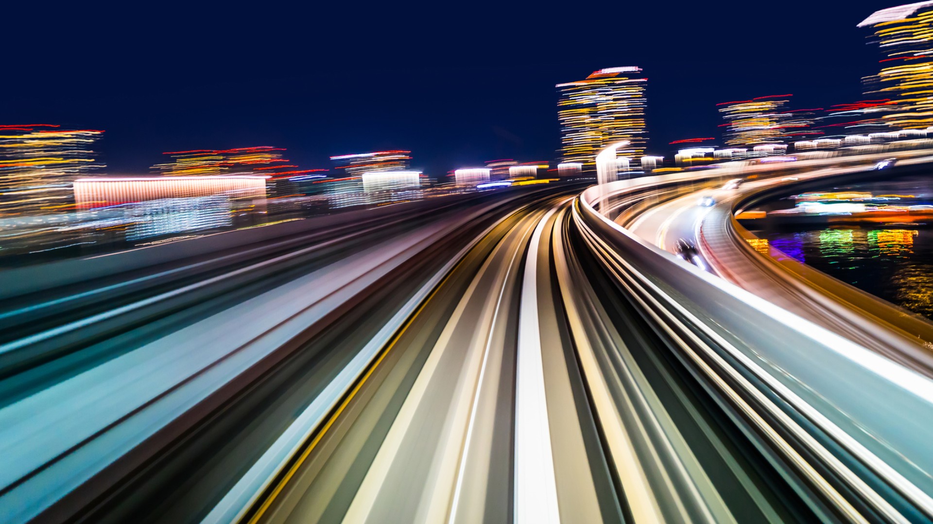 Dynamic night-time view of high-speed railway tracks with light trails symbolizing Knorr‑Bremse’s forward-looking vision and innovation