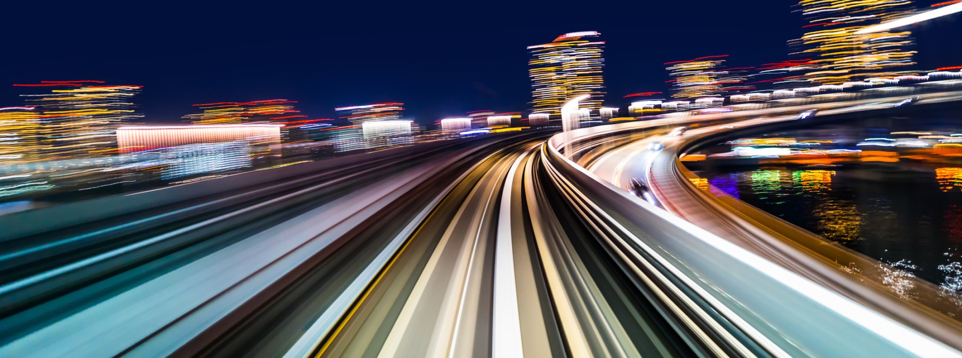 Dynamische Nachtaufnahme einer schnell fahrenden Bahnstrecke mit Lichterspuren – Symbol für Zukunft, Innovation und die Vision von Knorr‑Bremse