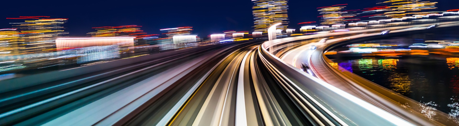 Dynamische Nachtaufnahme einer schnell fahrenden Bahnstrecke mit Lichterspuren – Symbol für Zukunft, Innovation und die Vision von Knorr‑Bremse