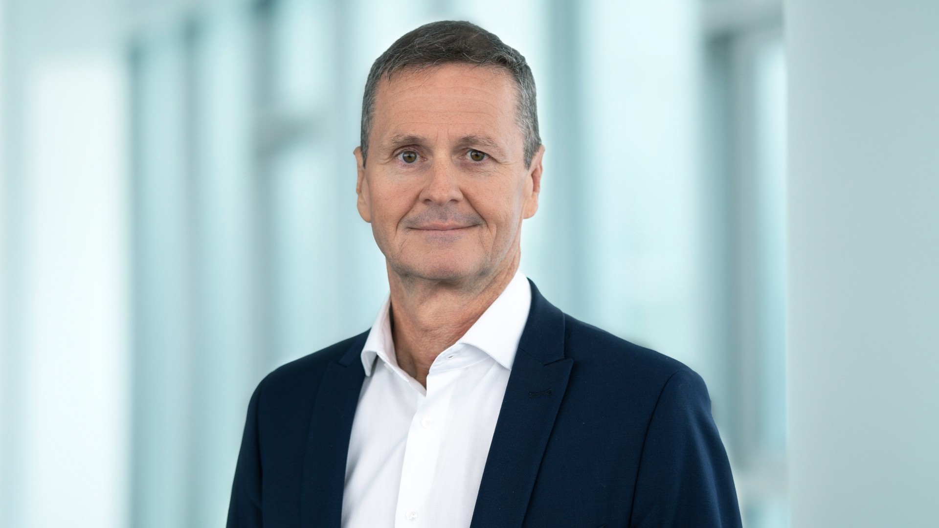 Porträtfoto eines Vorstandsmitglieds der Knorr‑Bremse AG mit Verantwortlichkeit für Finanzen, Accounting, Controlling, Steuern, Treasury, M&A, Nachhaltigkeit und Investor Relations, im Business‑Anzug vor einem modernen Büro-Hintergrund