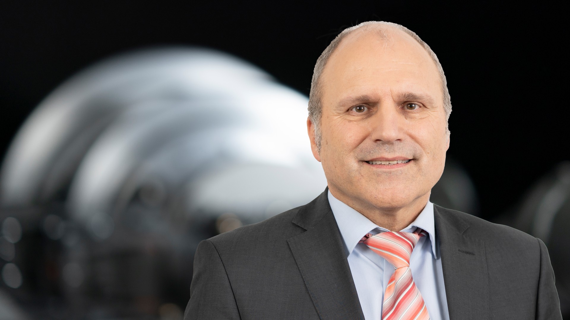 Business portrait of a supervisory board member of Knorr-Bremse AG in front of an industrial machinery component