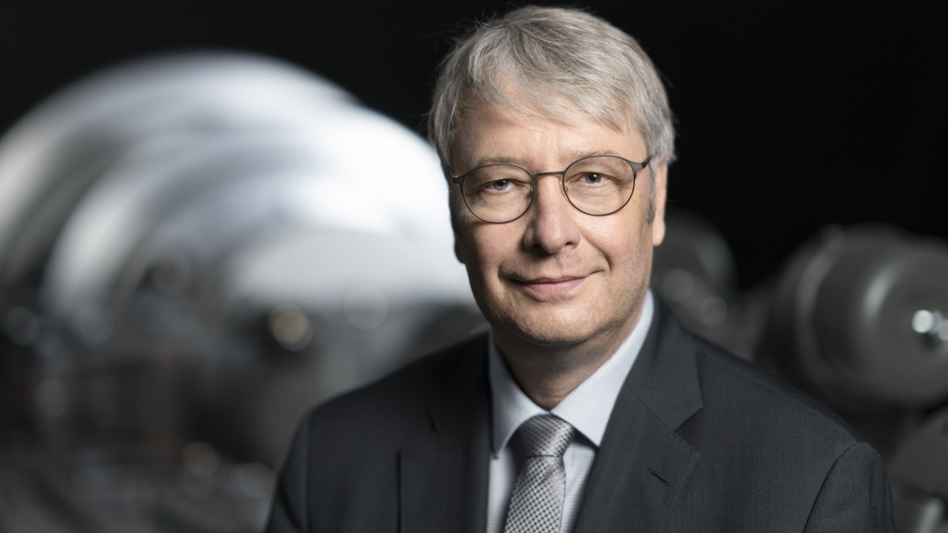 Business portrait of a supervisory board member of Knorr-Bremse AG in front of an industrial machinery component