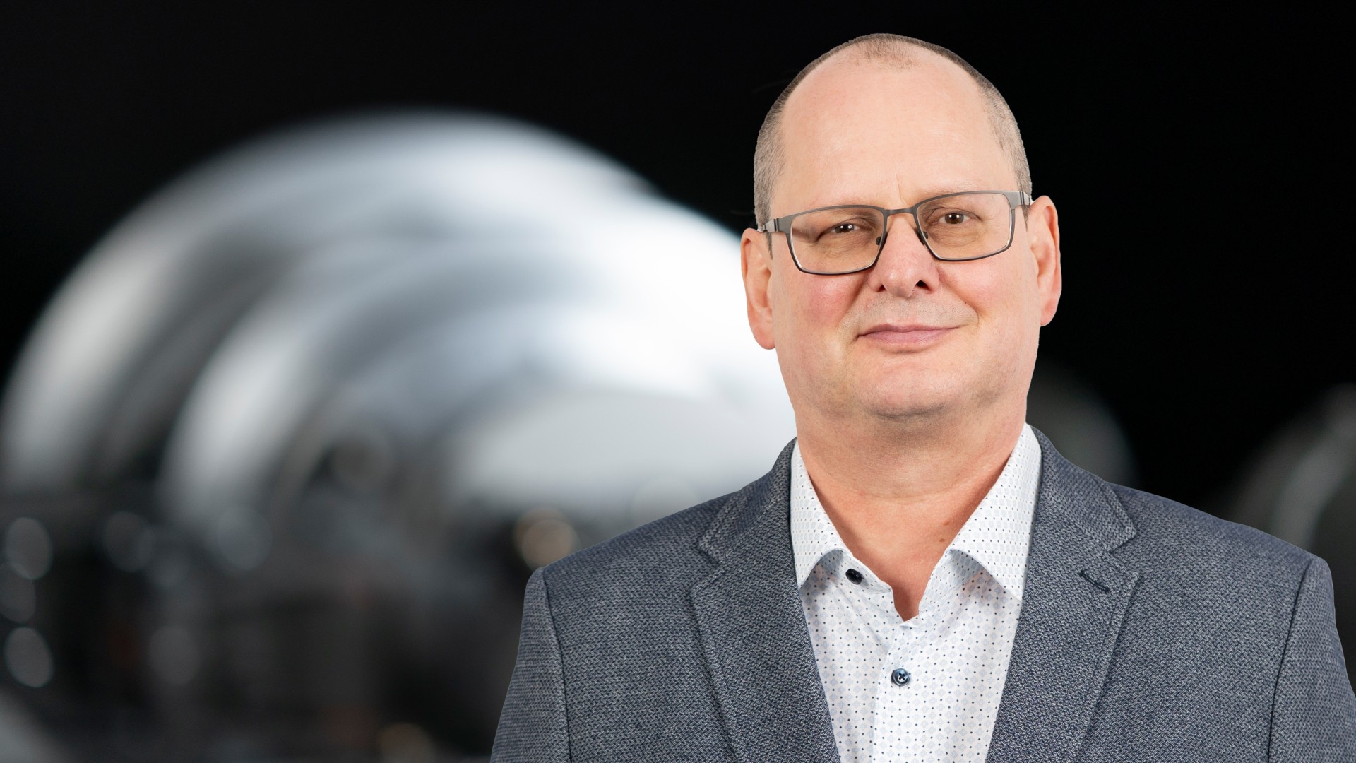 Business‑Portrait eines Aufsichtsratsmitglieds der Knorr‑Bremse AG vor industrieller Maschinenkomponente