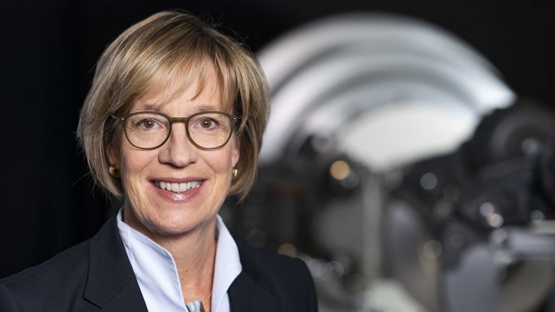 Business portrait of a supervisory board member of Knorr-Bremse AG in front of an industrial machinery component