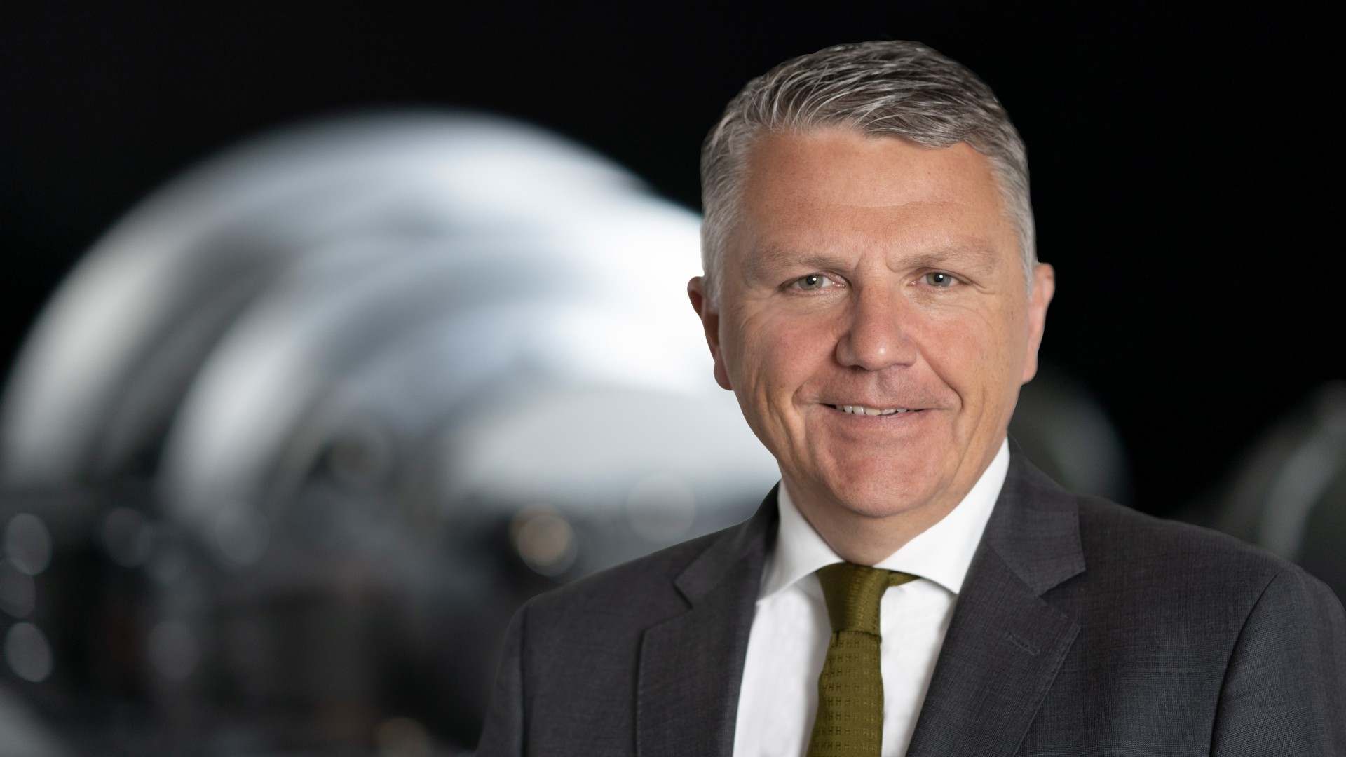 Business portrait of the Deputy Chairman of the Supervisory Board of Knorr-Bremse AG in front of an industrial machinery component
