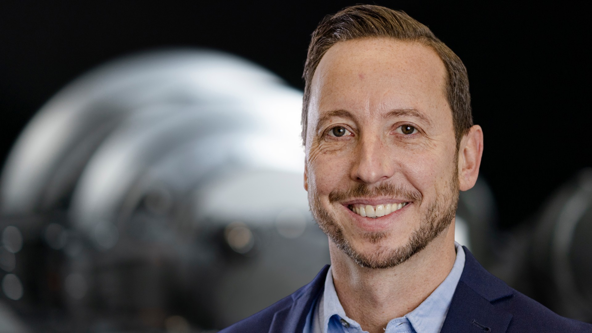 Business portrait of a supervisory board member of Knorr-Bremse AG in front of an industrial machinery component