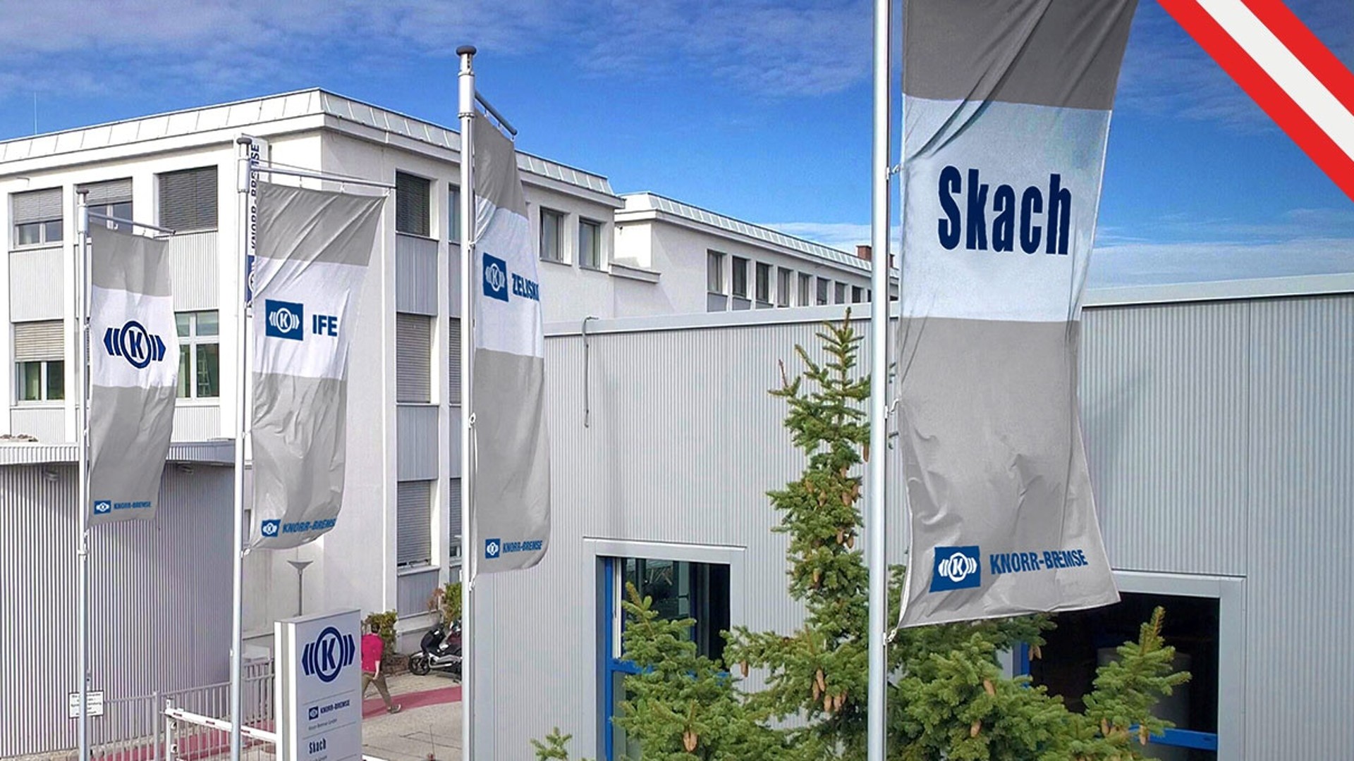 Gebäude mit Logofahnen im Vordergrund des österreichischen Knorr-Bremse Standorts in Mödling