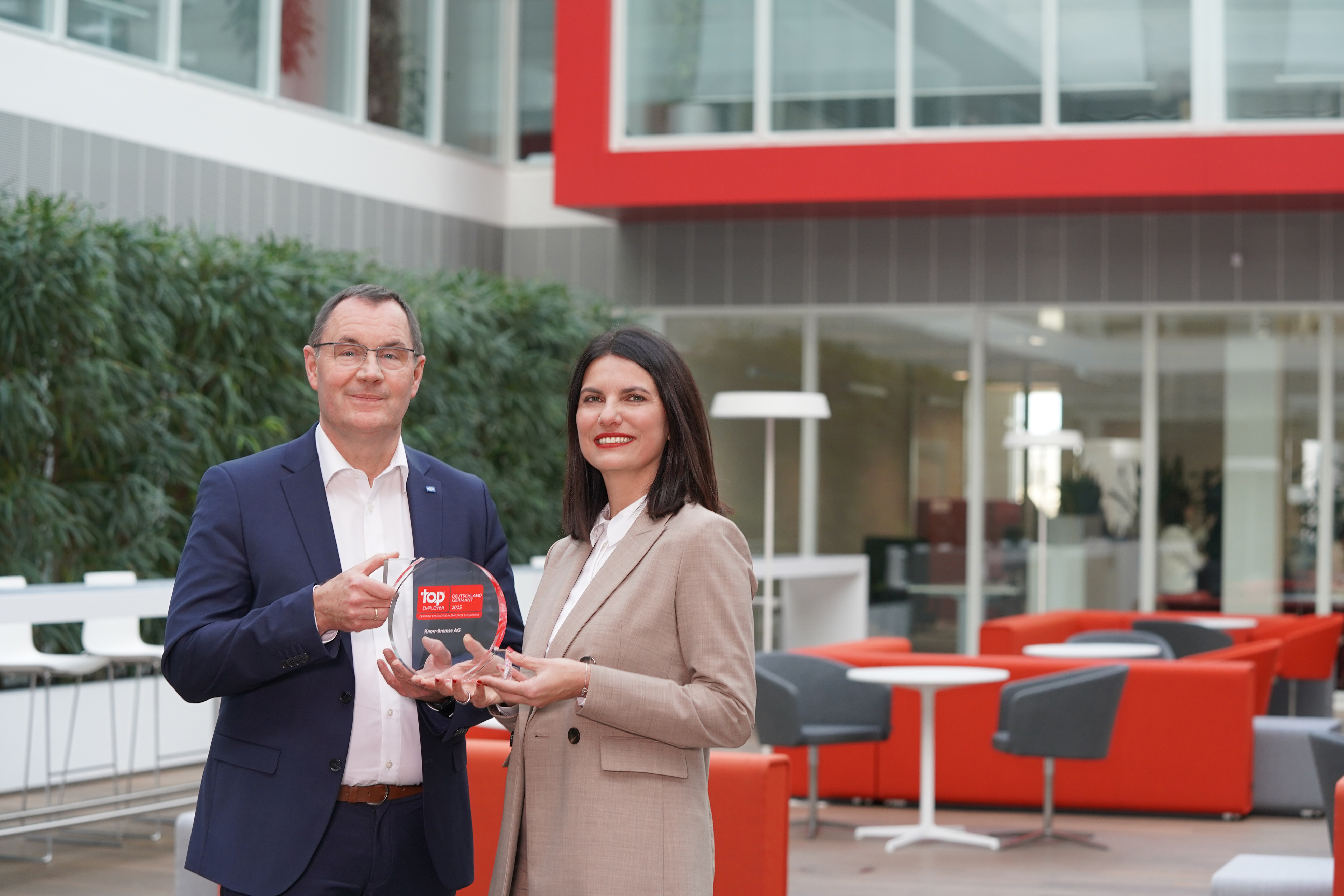 Klaus Remmler, Senior Vice President Corporate HR at Knorr-Bremse AG, and Berna Tulga-Akcan, HR Specialist University Marketing, jointly hold the Top Employer Award in their hands.