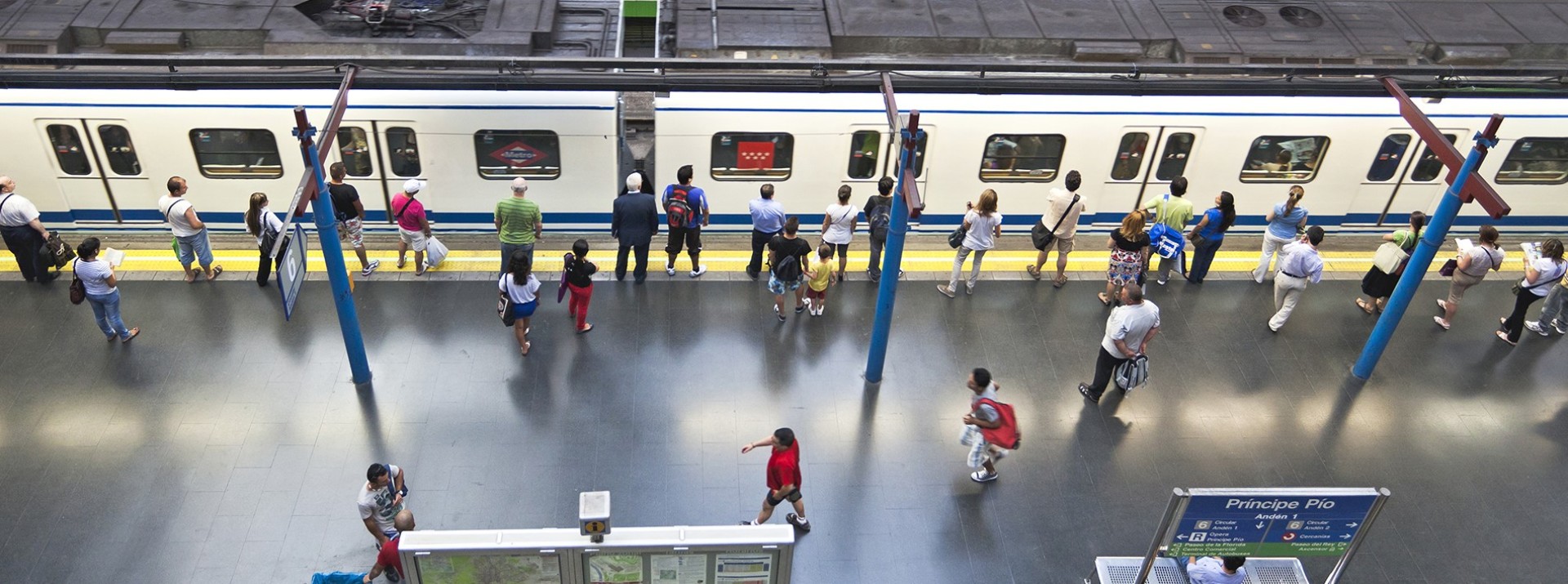Passagiere stehen am Bahnsteig vor einer U-Bahn in Madrid und warten darauf, dass sich die Türen zum Einstieg öffnen.
