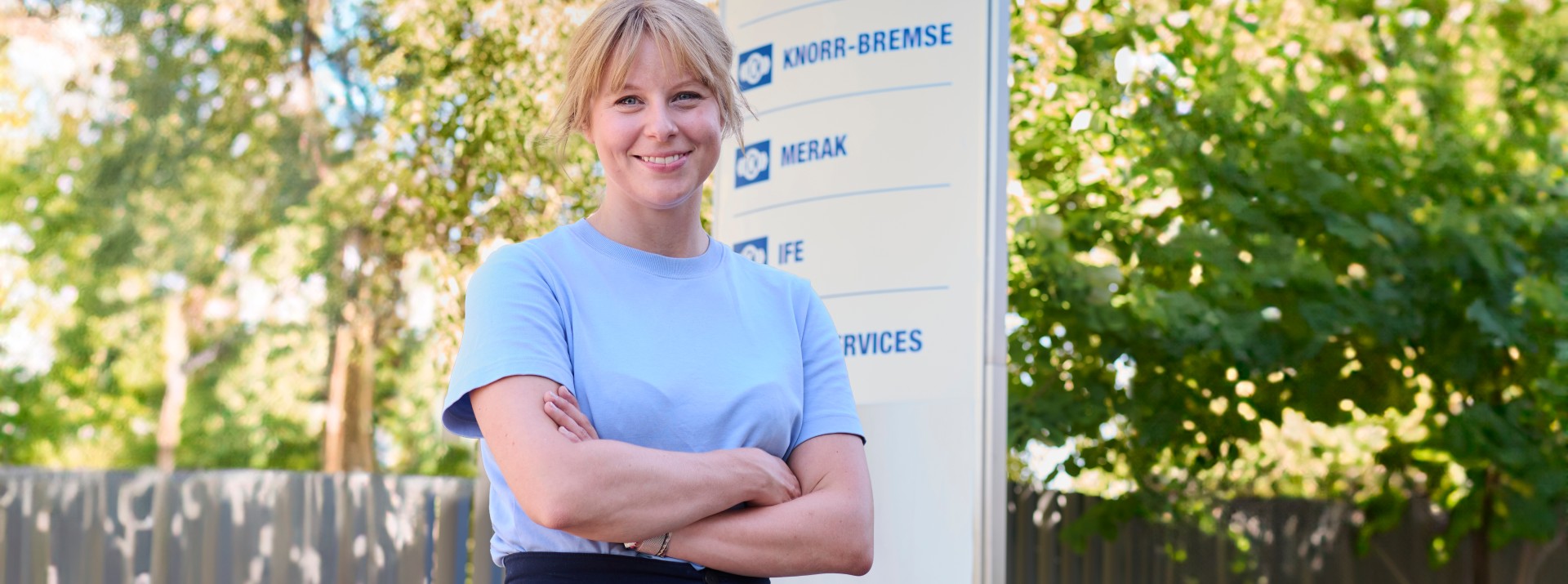 Laura Hajek, Trainee bei Knorr-Bremse, steht vor dem Firmenschild des Knorr-Bremse Standorts in Getafe, Spanien.