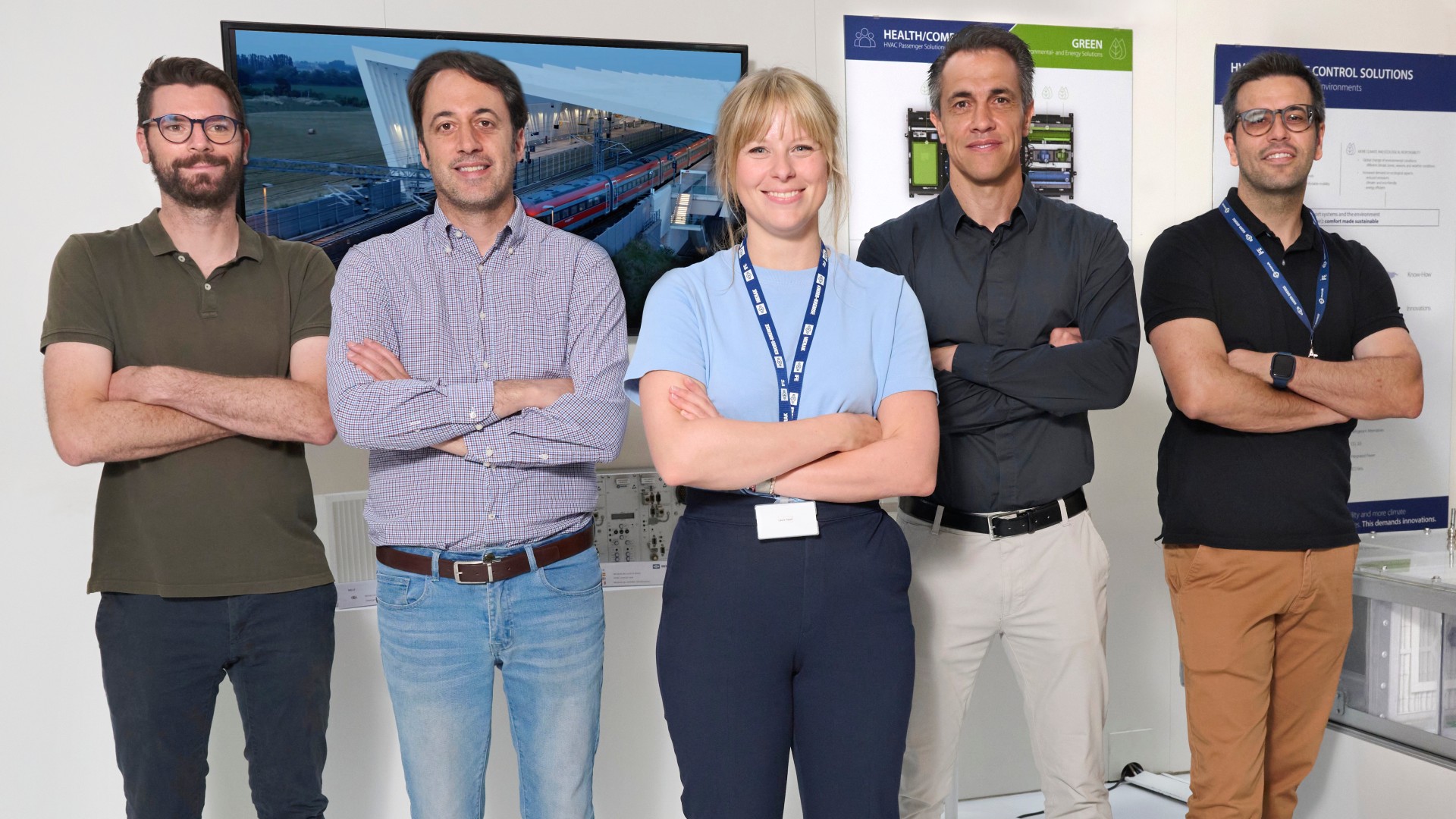 Laura Hajek stands with her colleagues from the project team in front of a poster and screen wall at the Knorr-Bremse plant in Getafe, Spain.