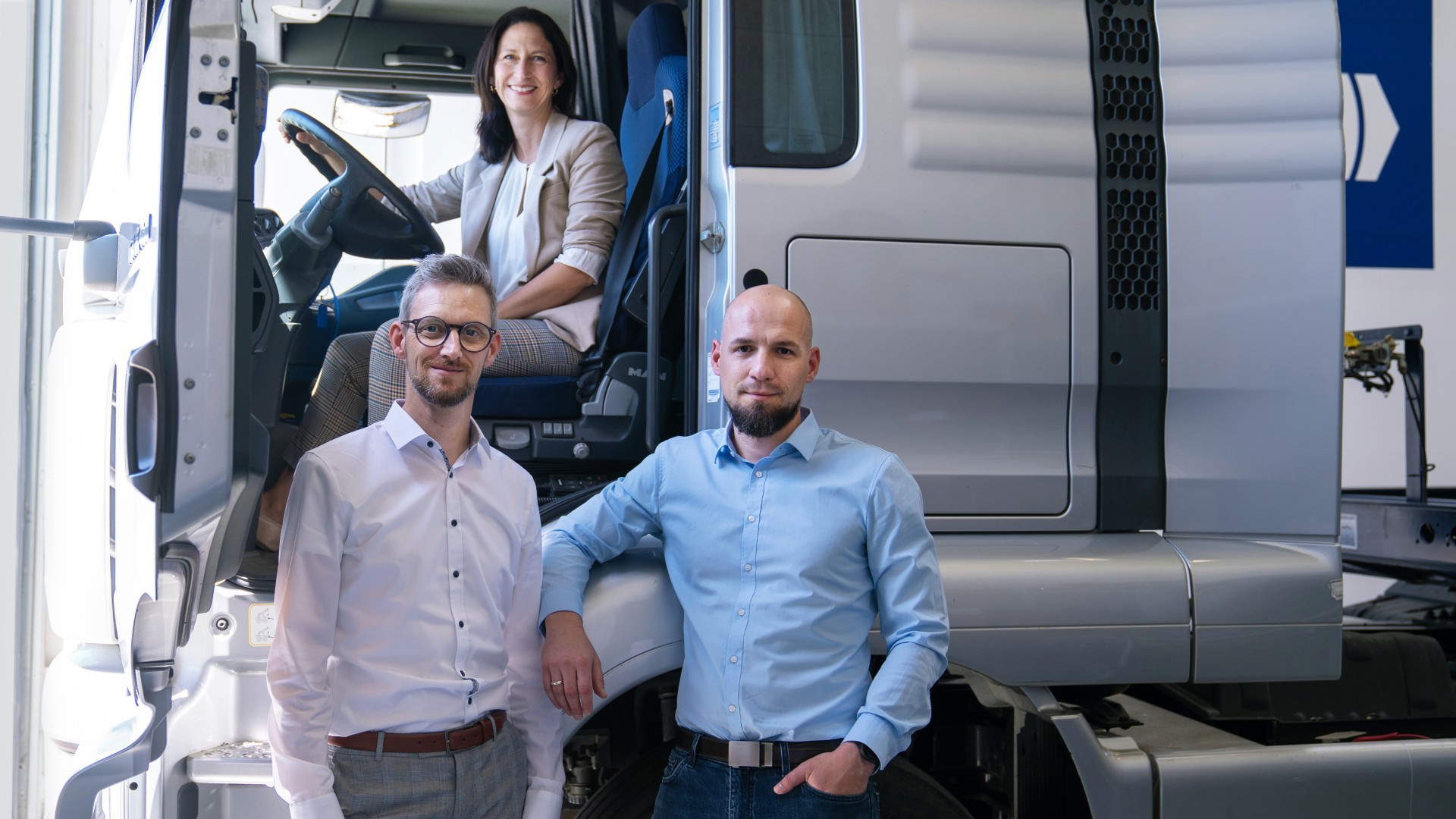 Group of people in a truck workshop in front of a commercial vehicle in the context of circular economy and workshop efficiency