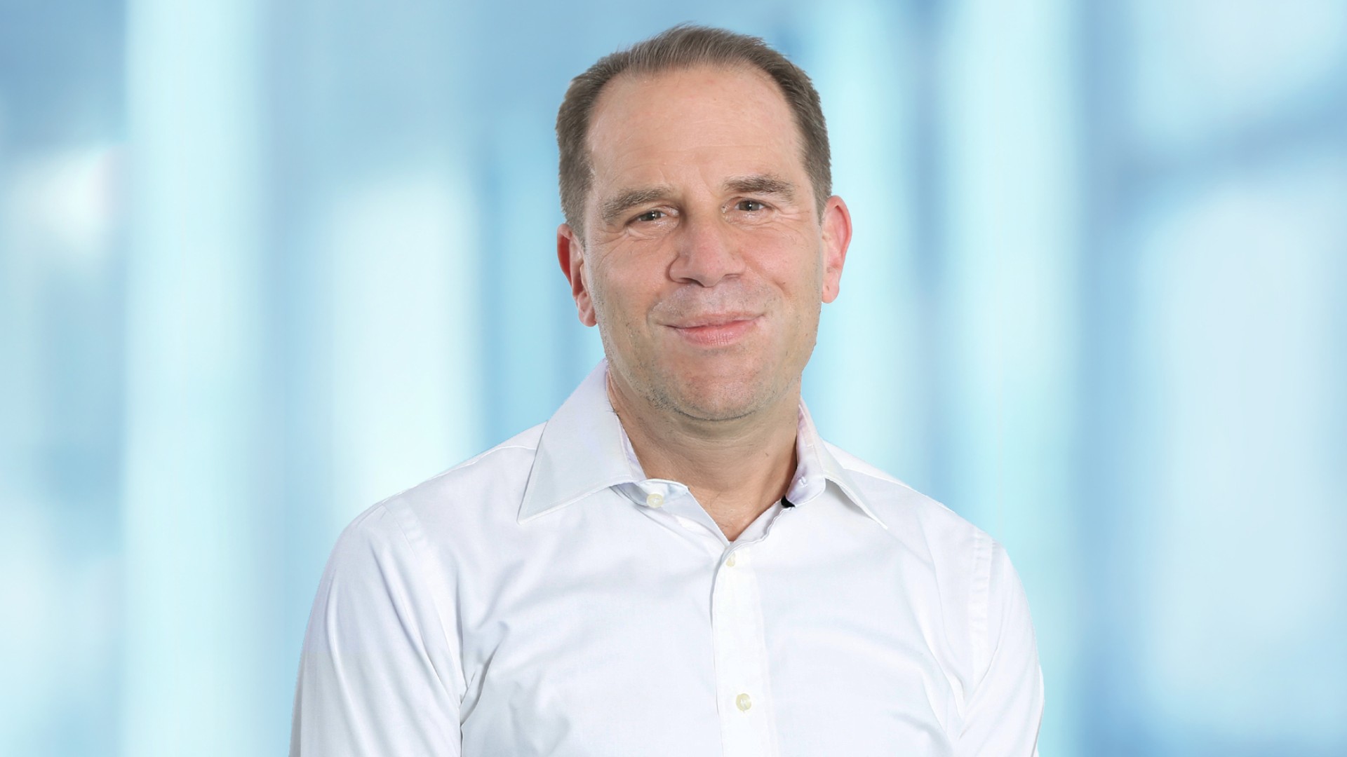Portrait of a person in light-colored clothing against a neutral, modern background in the context of digital aftermarket solutions
