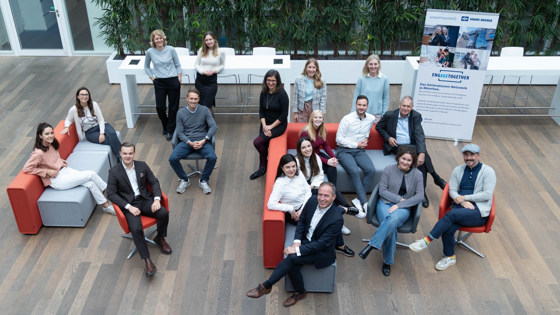 Core team of the Generations@KB network in Munich during a group meeting in a modern, open office environment with seating areas and an information poster in the background