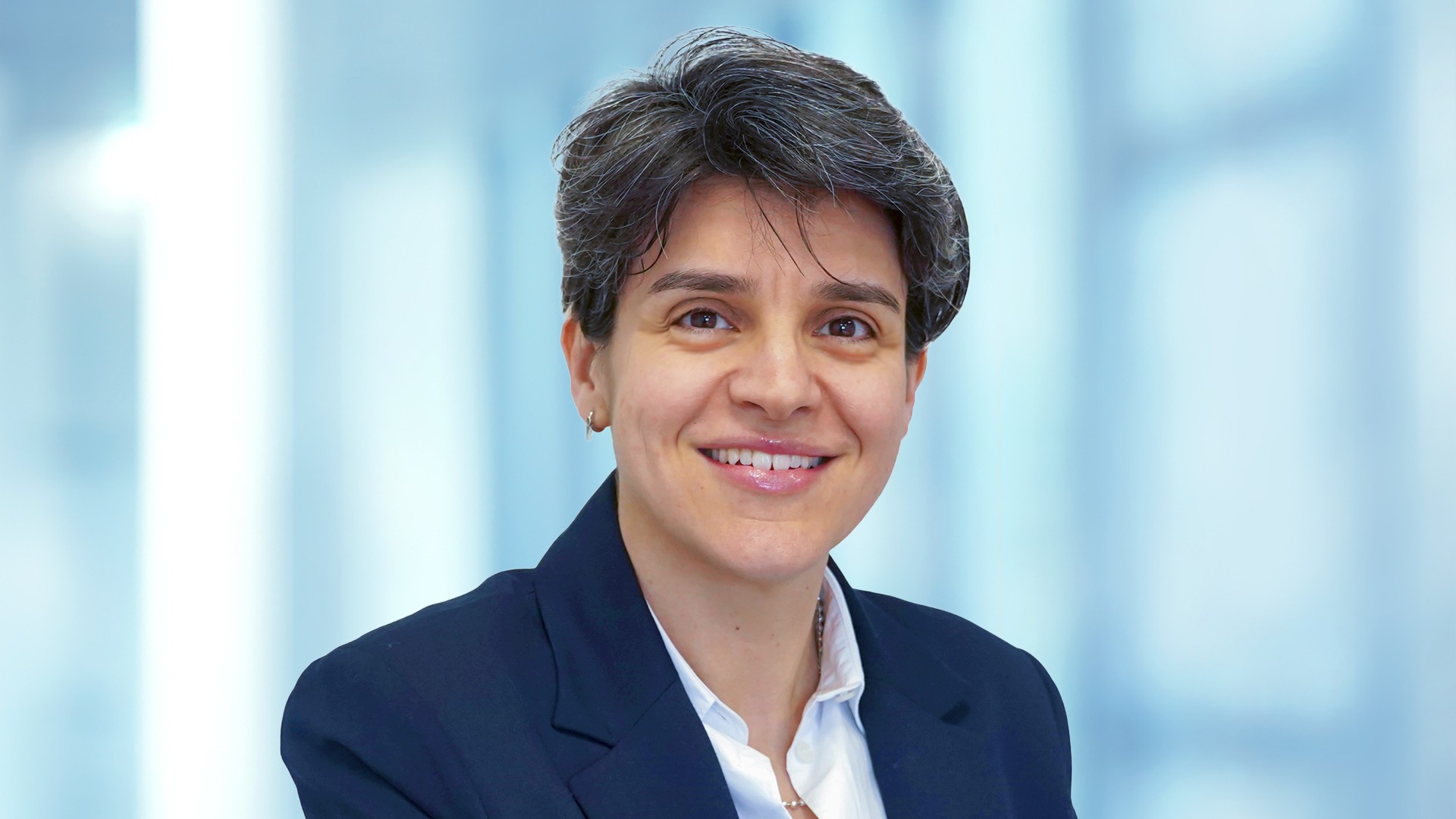 Employee portrait in business attire in front of a modern office background