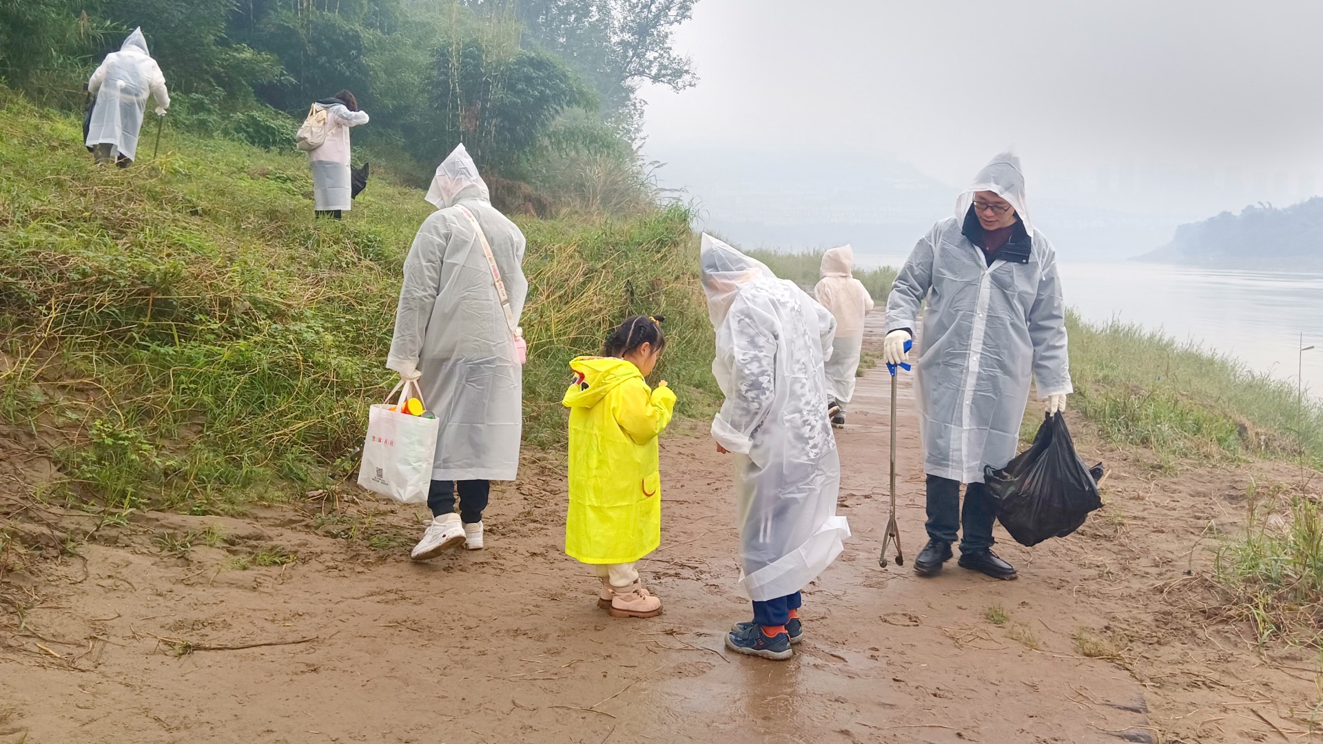 Employees from Chongqing and their families jointly collect litter along a riverbank