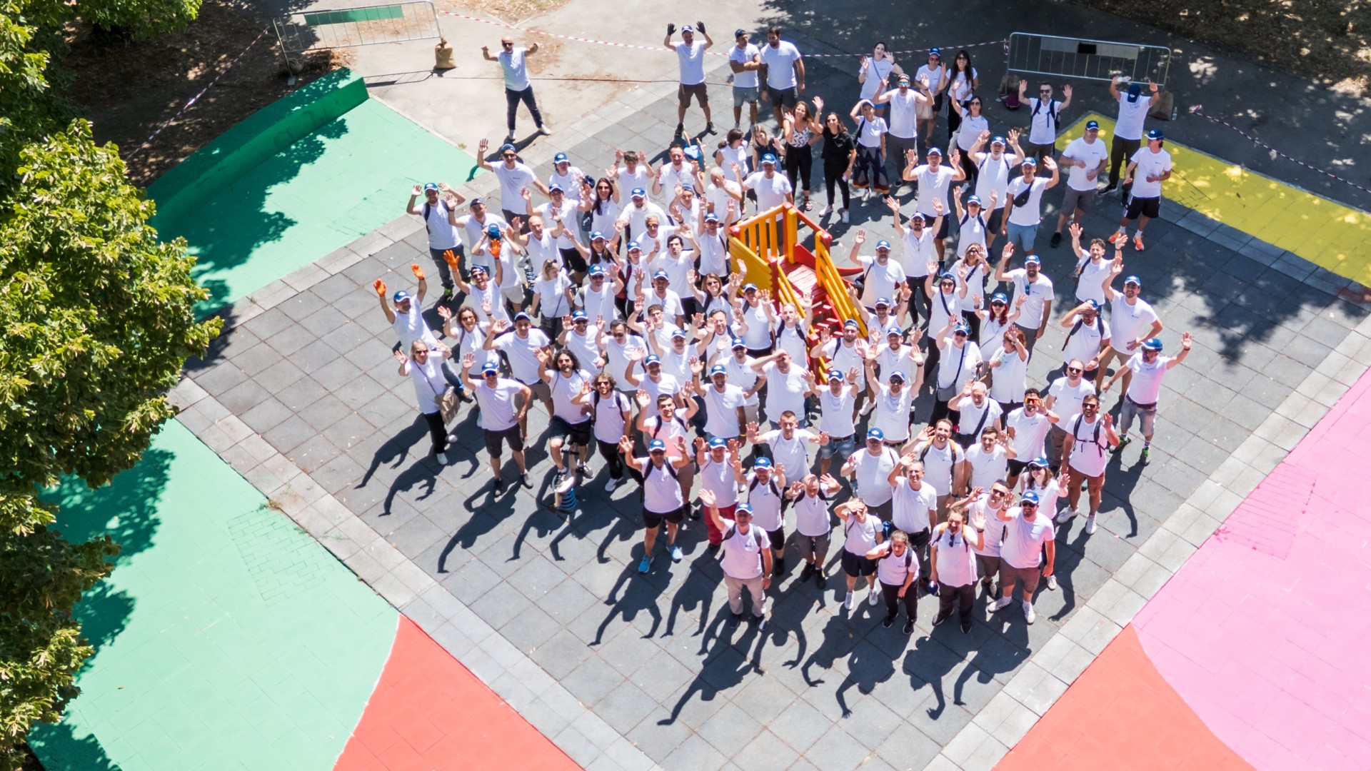 Group photo of waving employees on a family and children’s playground that they restored after flooding